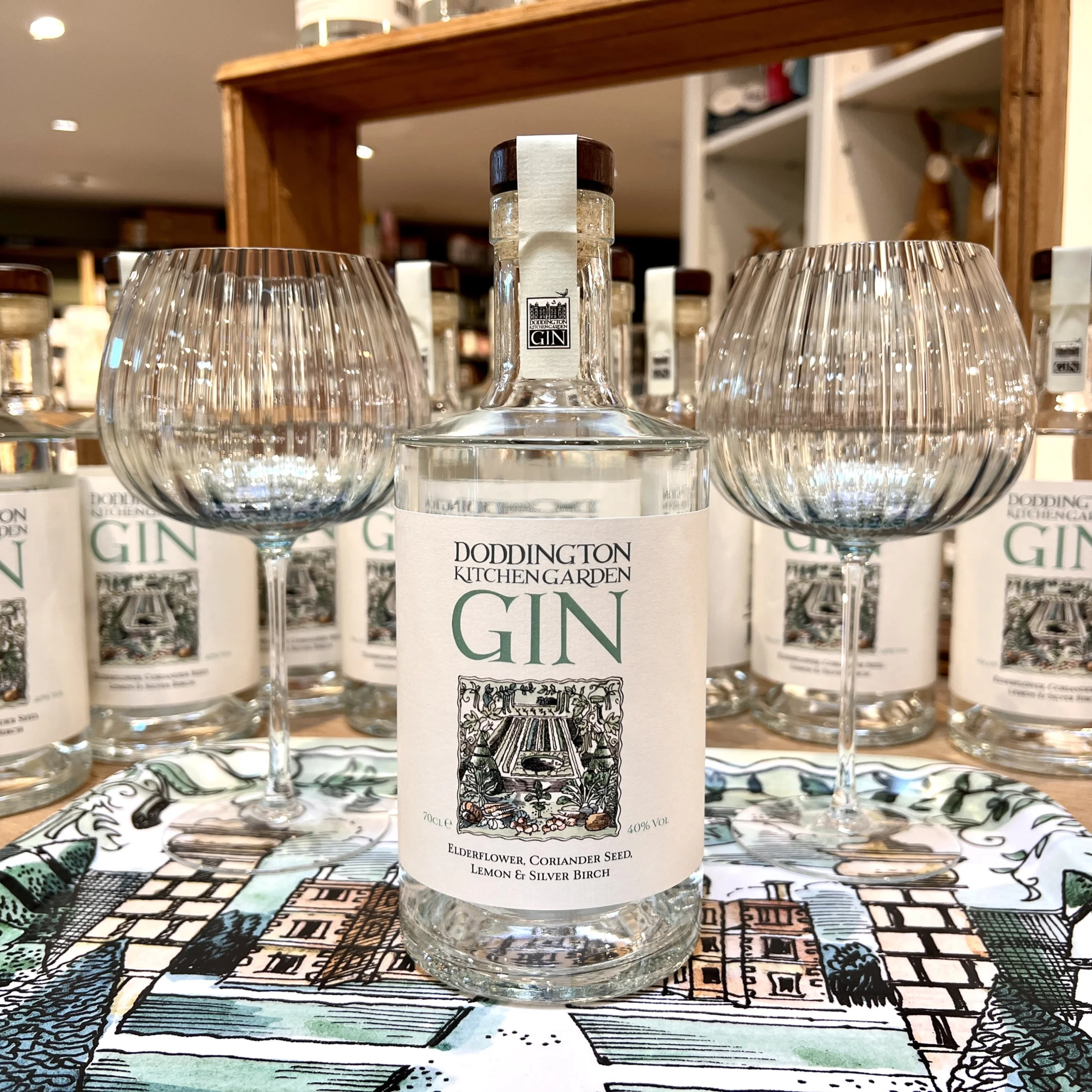 a glass bottle of doddington kitchen garden gin with two gin glasses