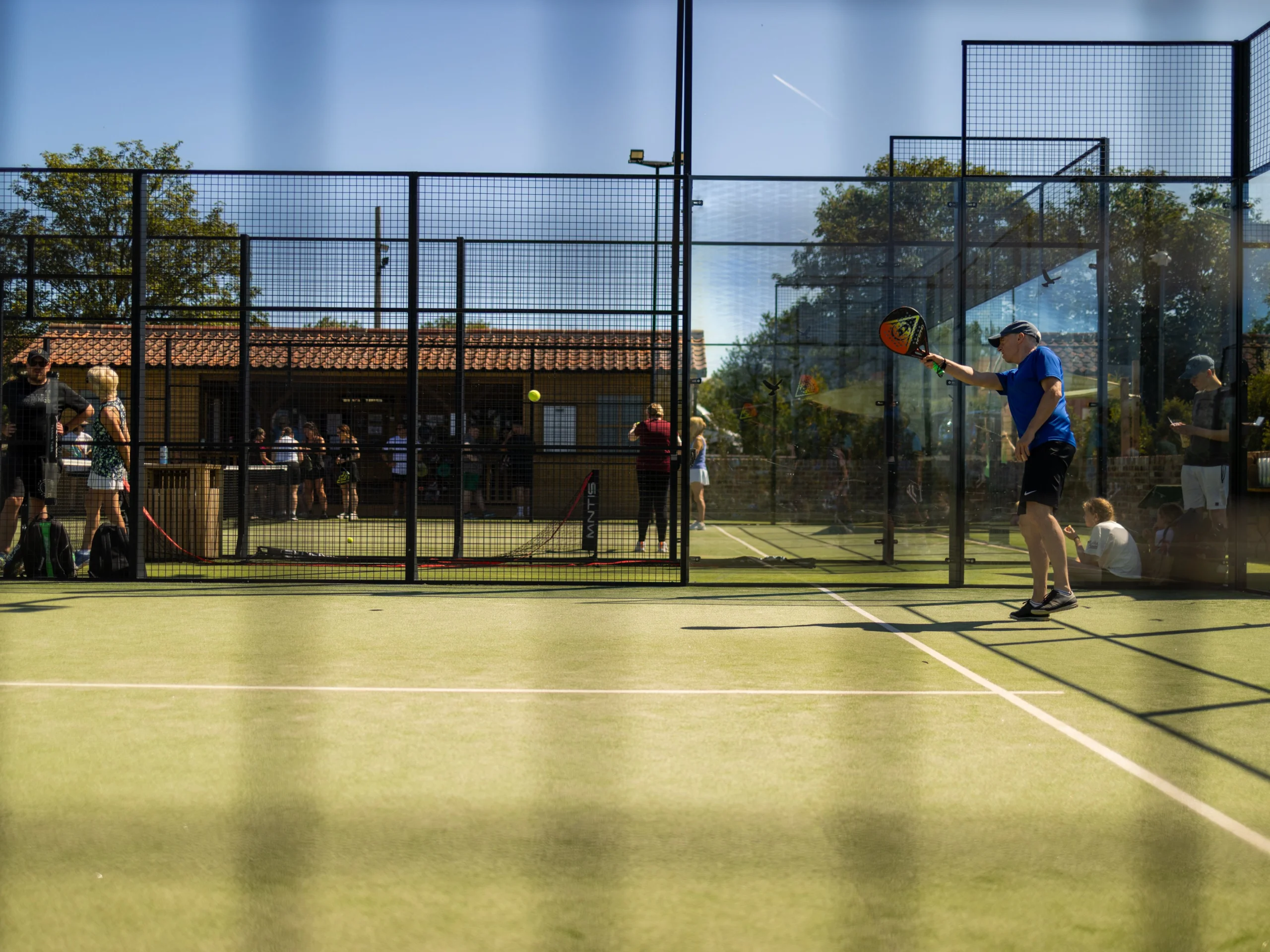 a man playing padel at doddington hall with blue sky