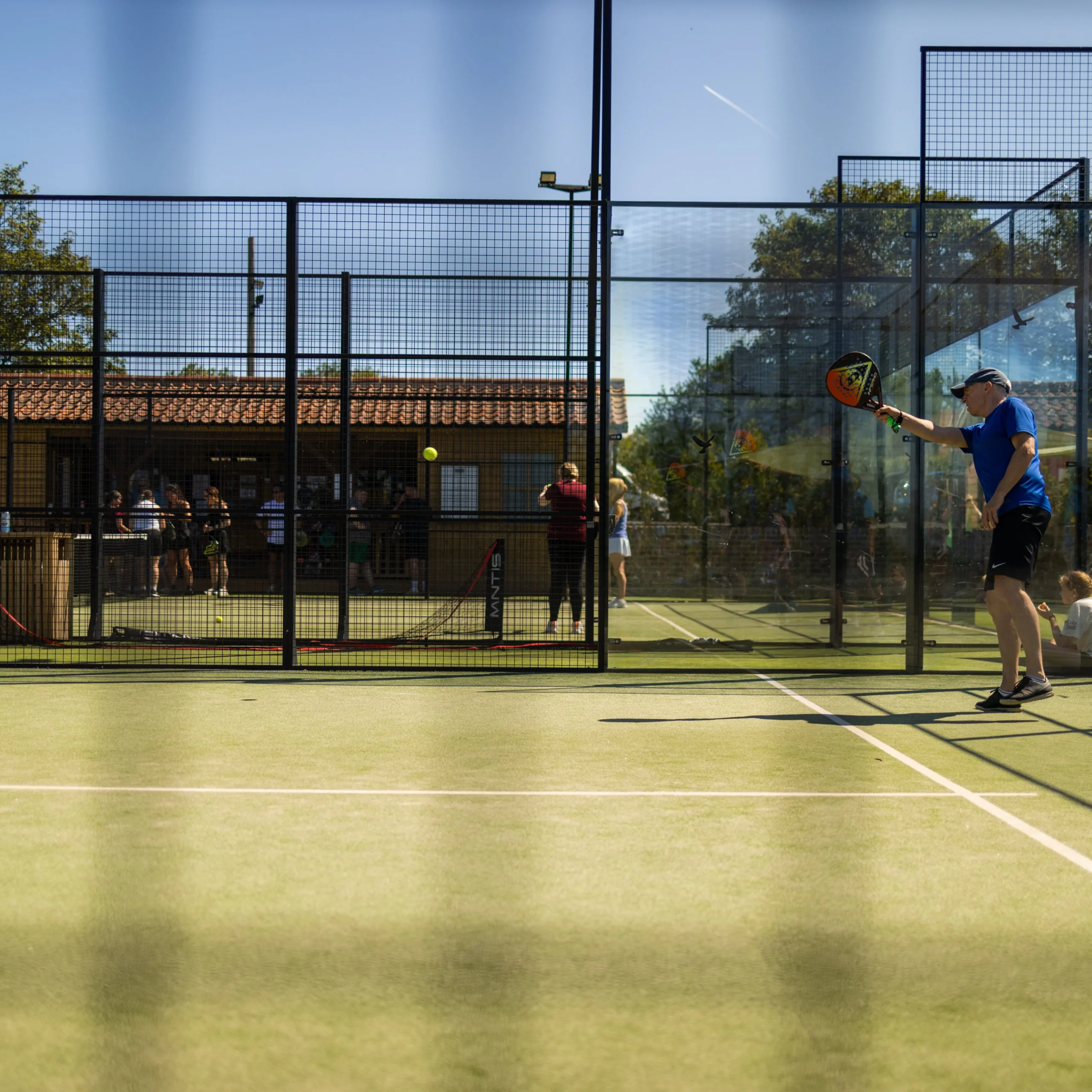 a man playing padel at doddington hall with blue sky
