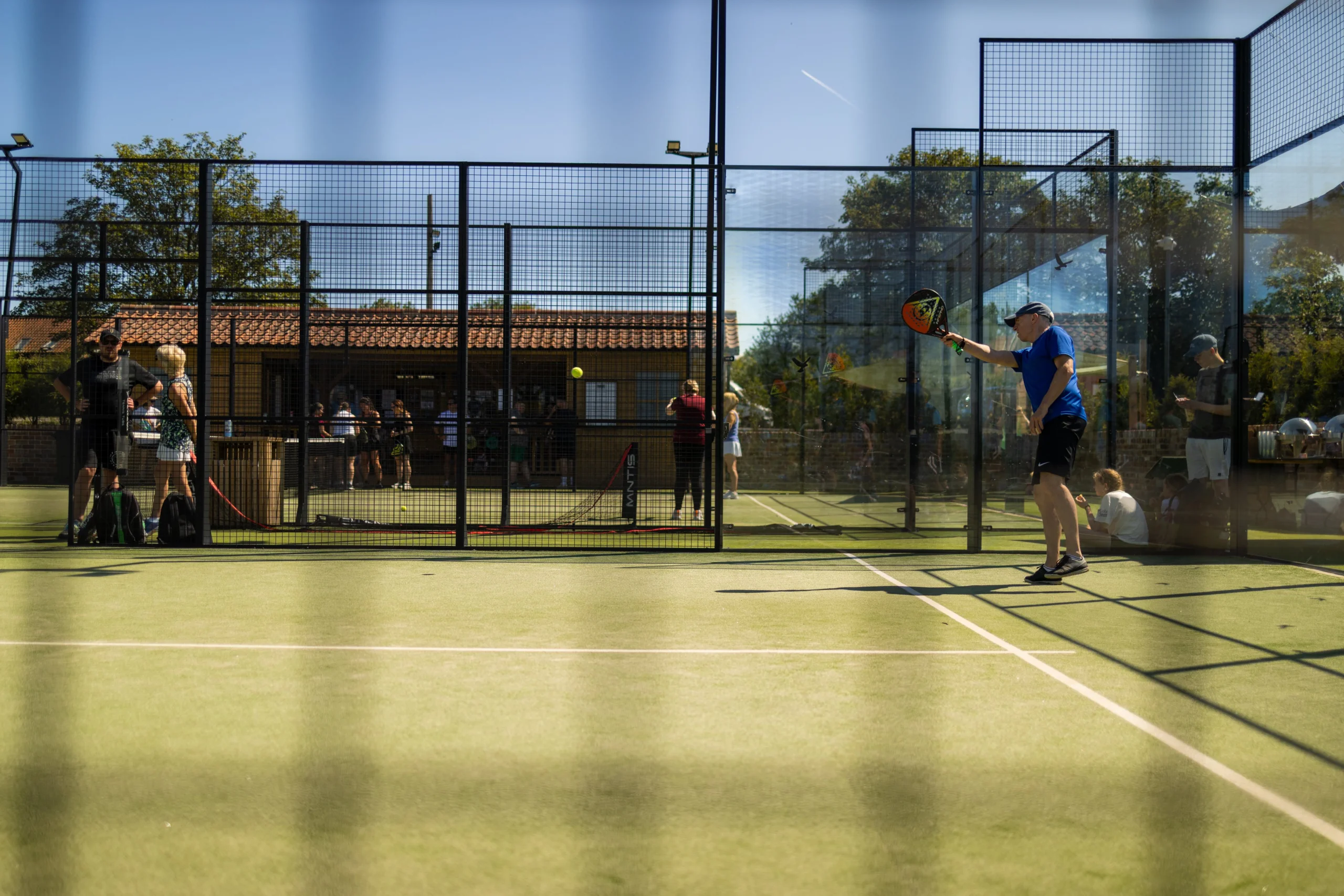 a man playing padel at doddington hall with blue sky