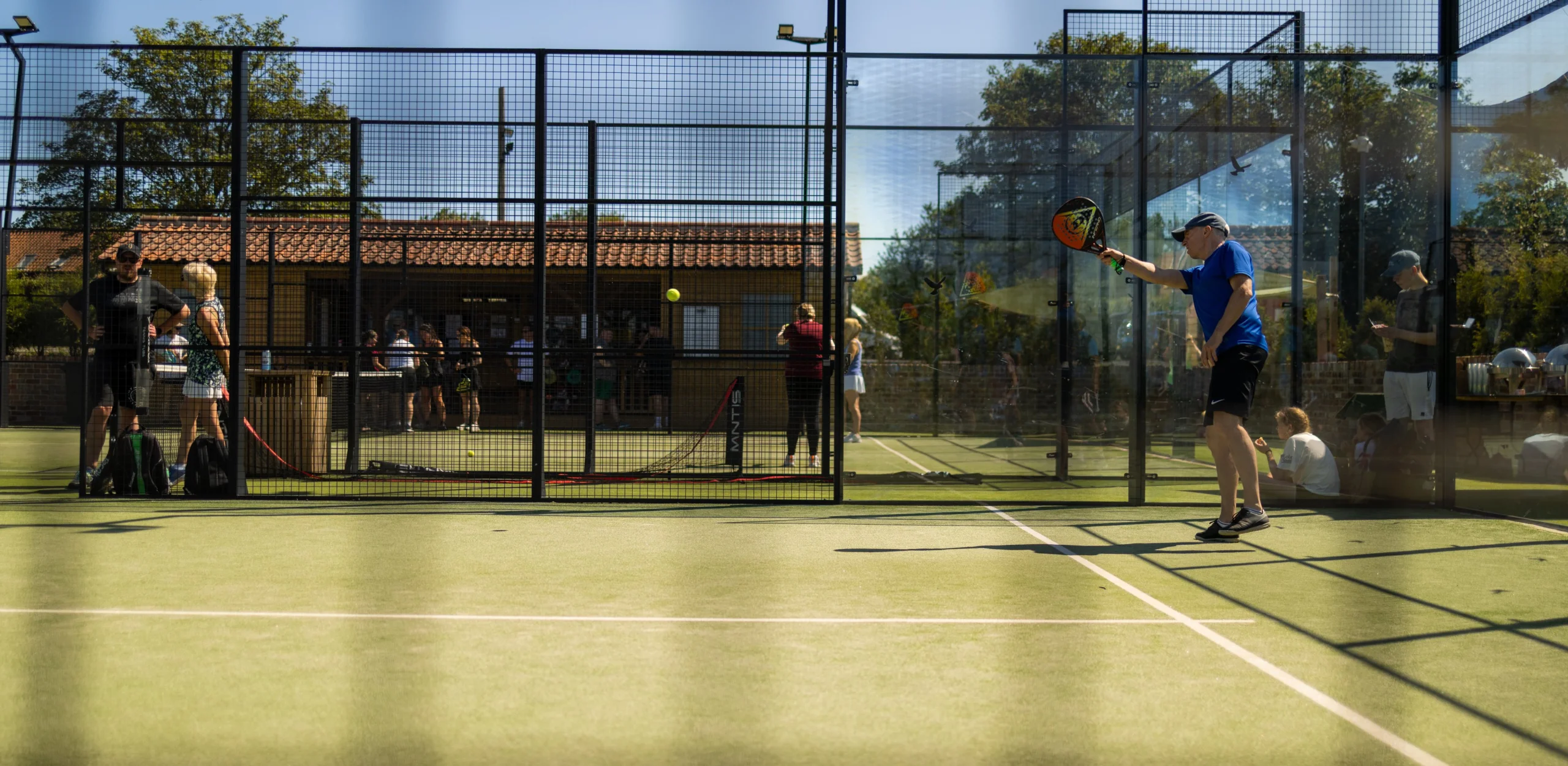 a man playing padel at doddington hall with blue sky