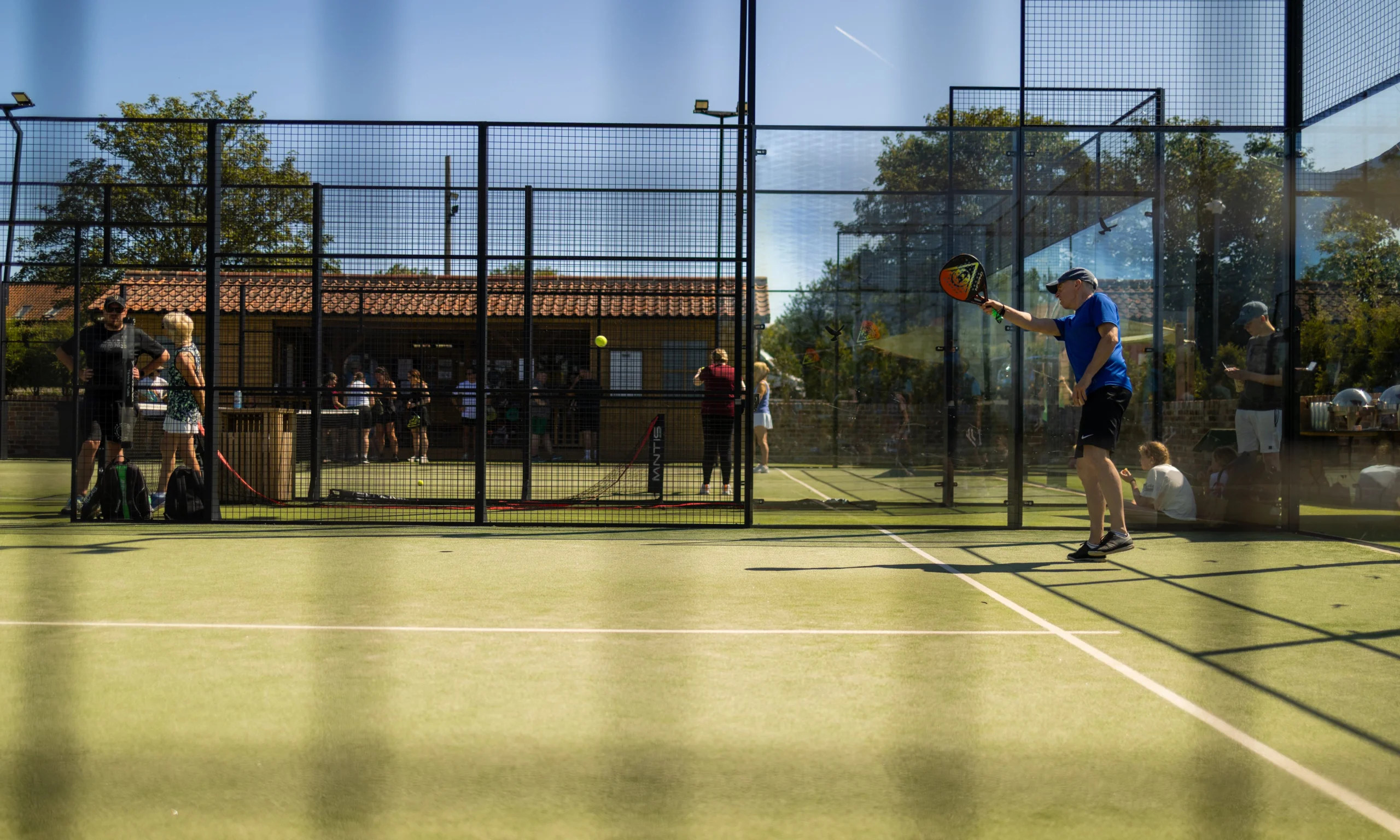 a man playing padel at doddington hall with blue sky