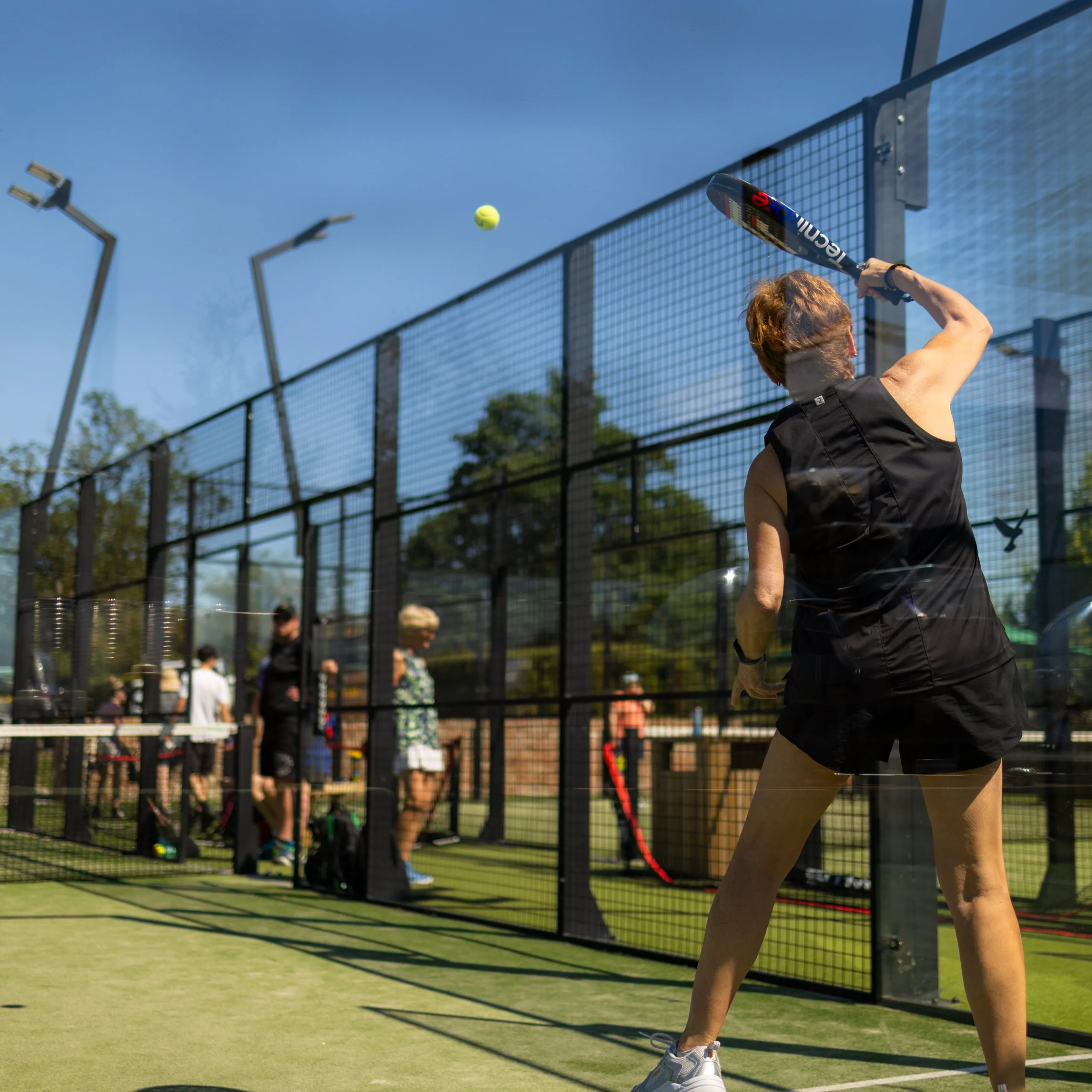 a lady serving a ball at doddington padel courts