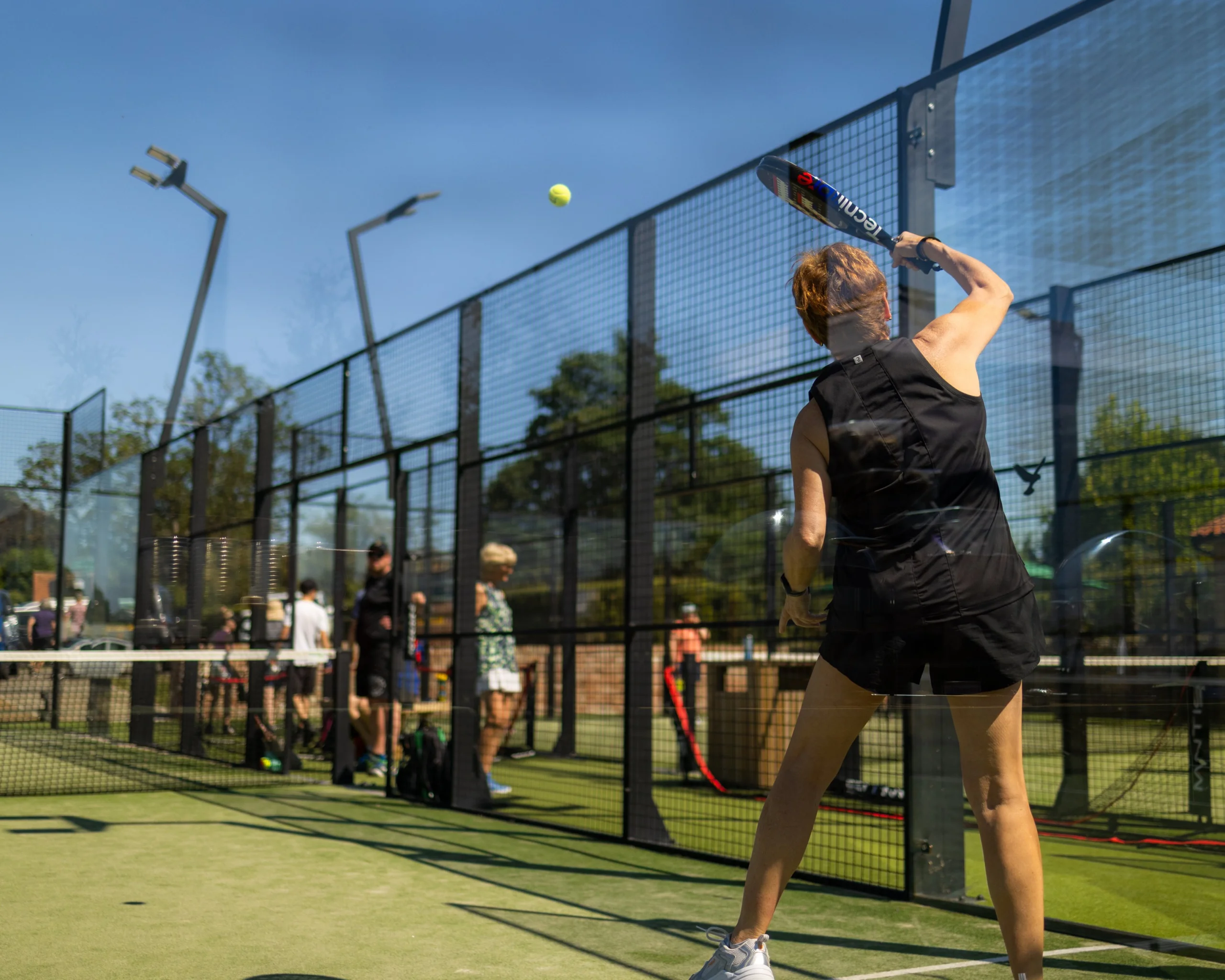 a lady serving a ball at doddington padel courts