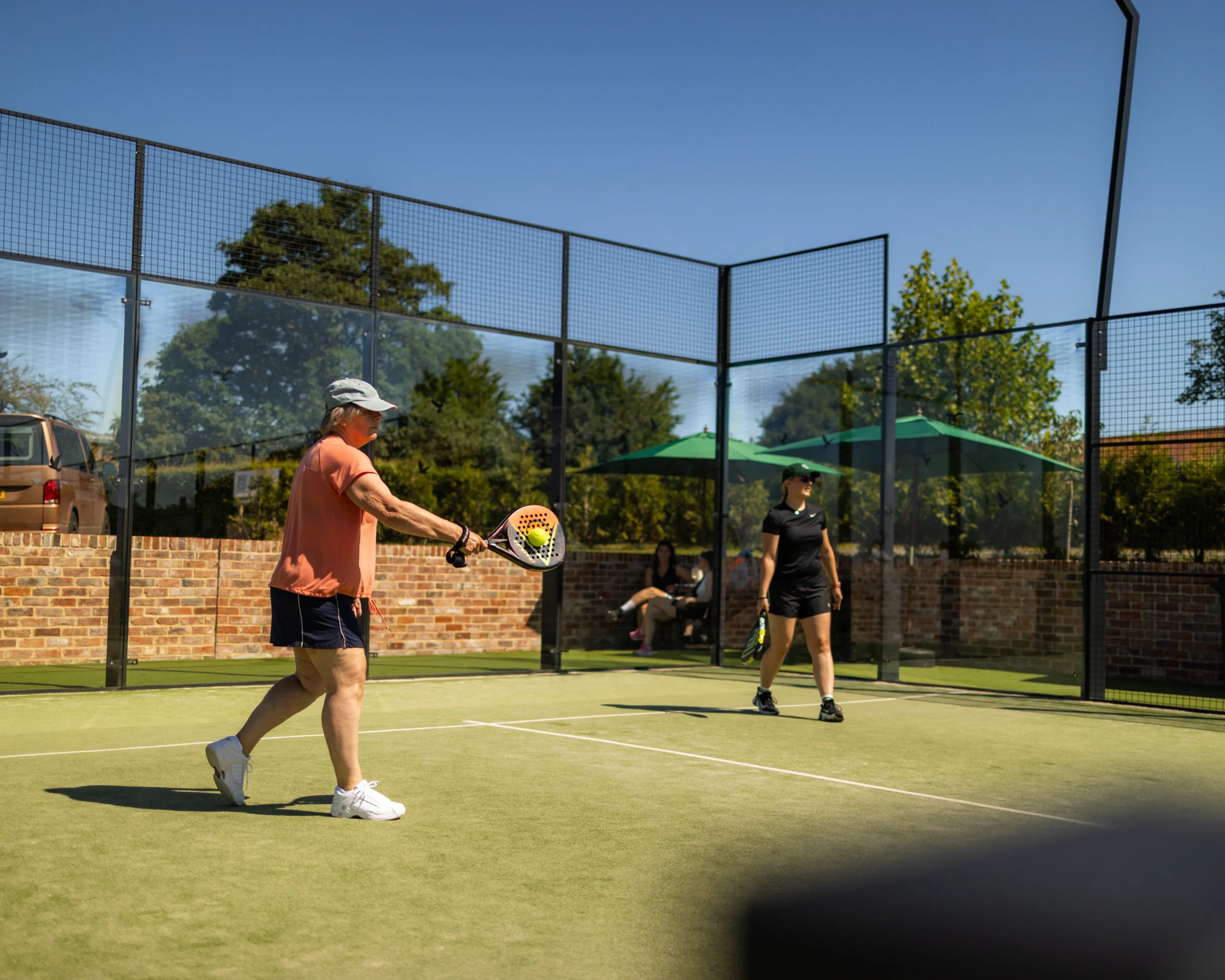women playing padel at doddington hall with blue sky