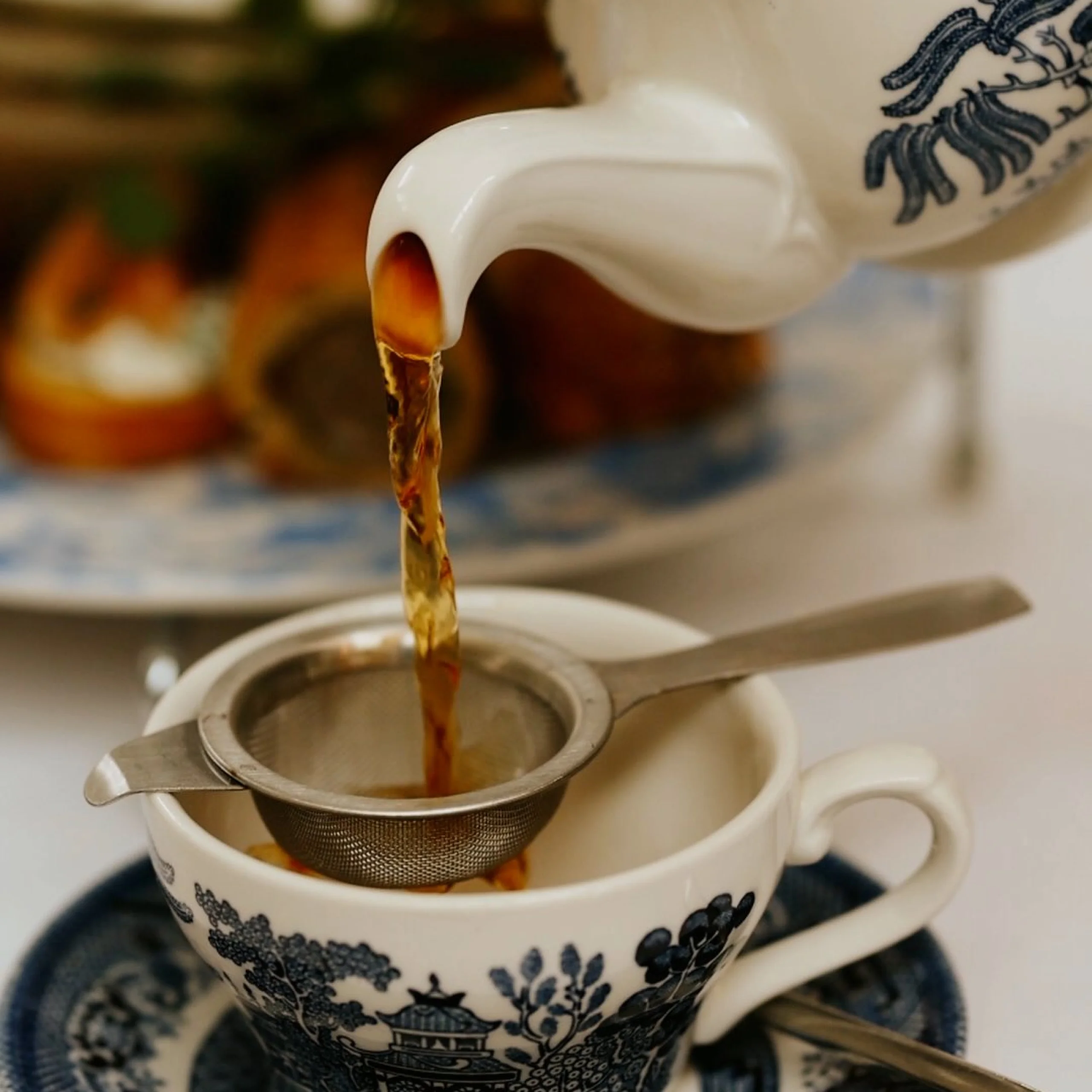 tea being poured from a teapot into a white and blue china cup doddington hall tea room