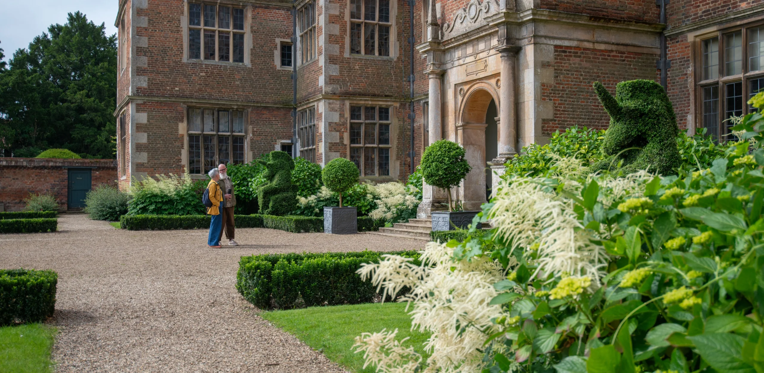 a couple admiring the east front of doddington hall
