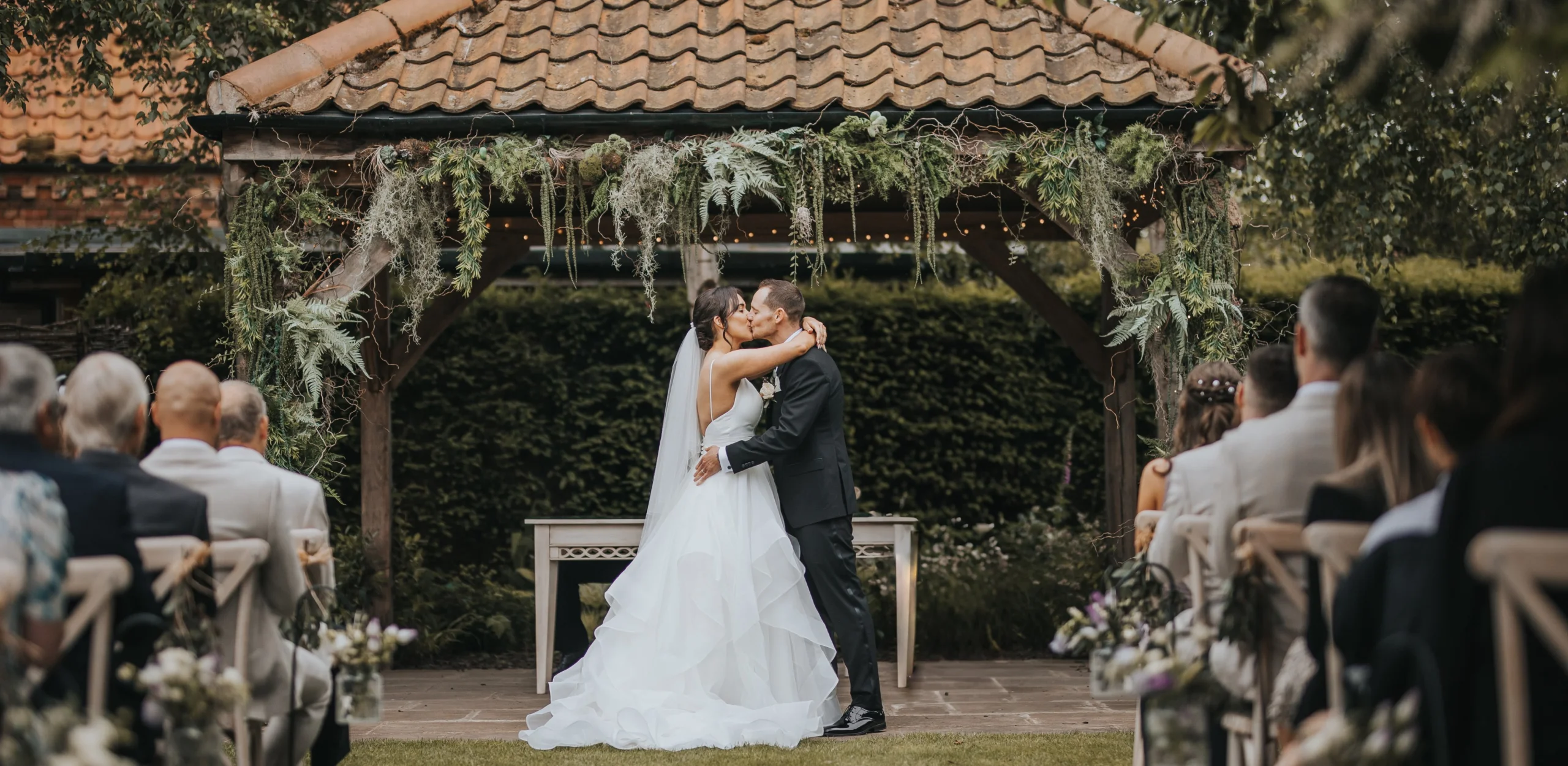 bride and groom kissing under the pergola in the garden at doddington hall estate
