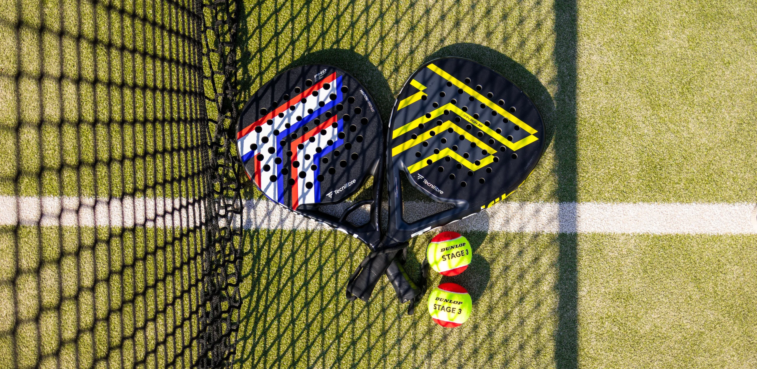 a close up of two padel rackets and balls next to a padel net at doddington hall