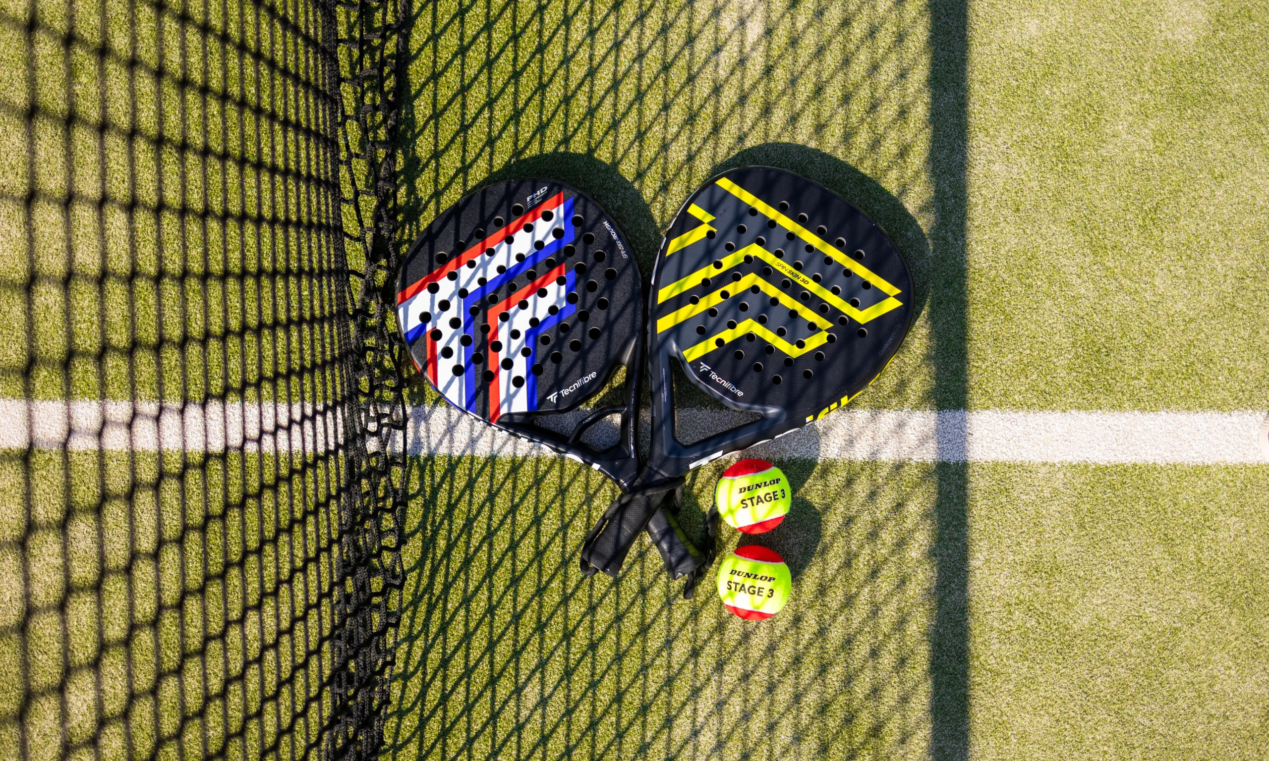 a close up of two padel rackets and balls next to a padel net at doddington hall