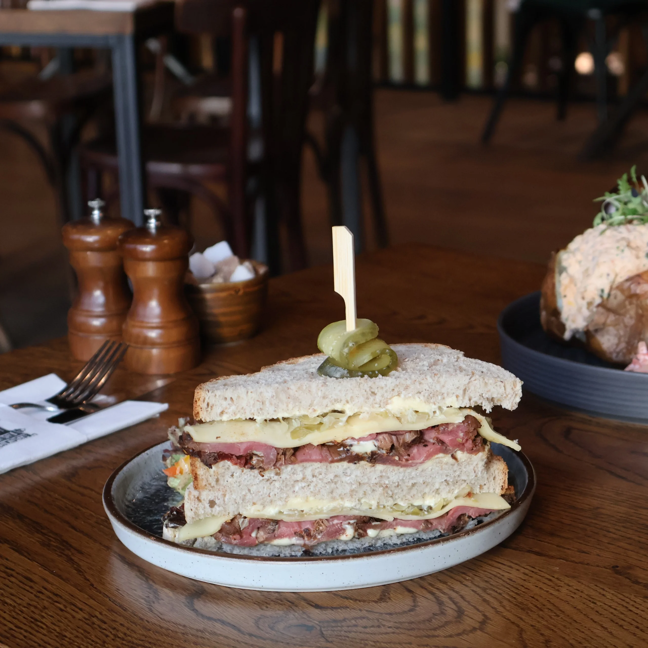 a pastrami and emmental sandwich with a pickle on top at doddington grain store cafe