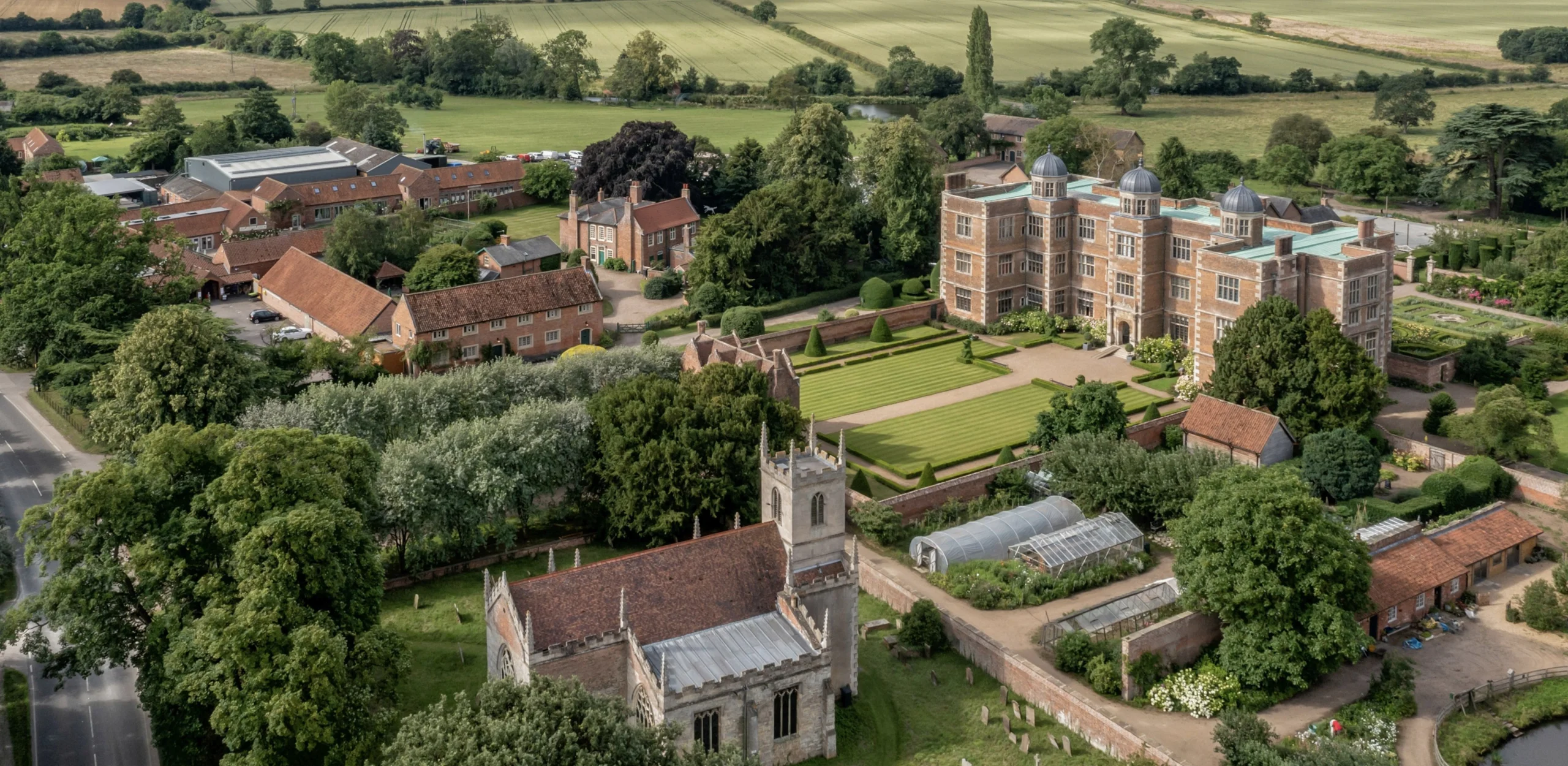 an aerial image of doddington hall with the sprawling country estate and church in the foreground