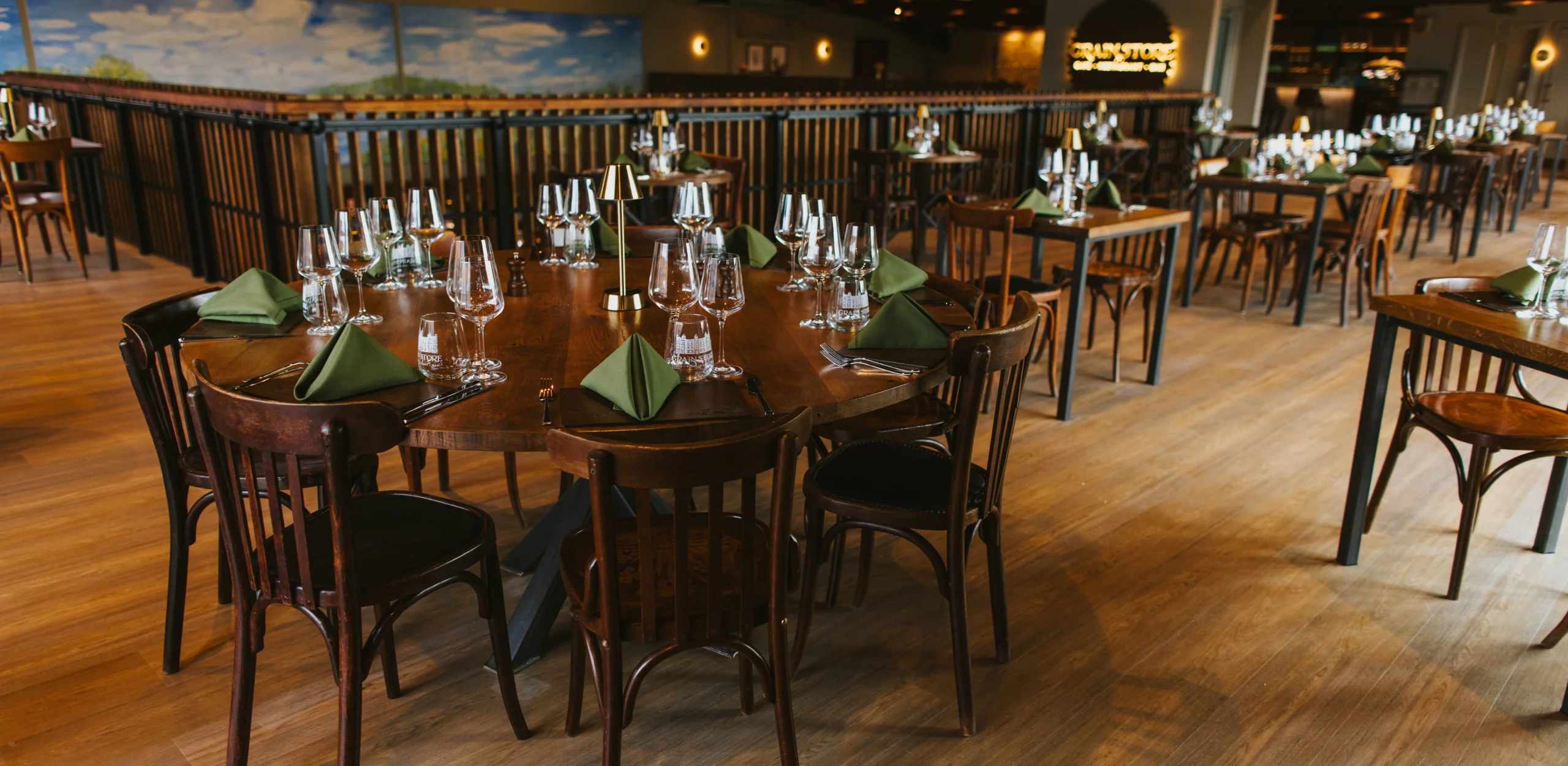 wooden tables setup with glasses and napkins for a supper club at doddington grain store