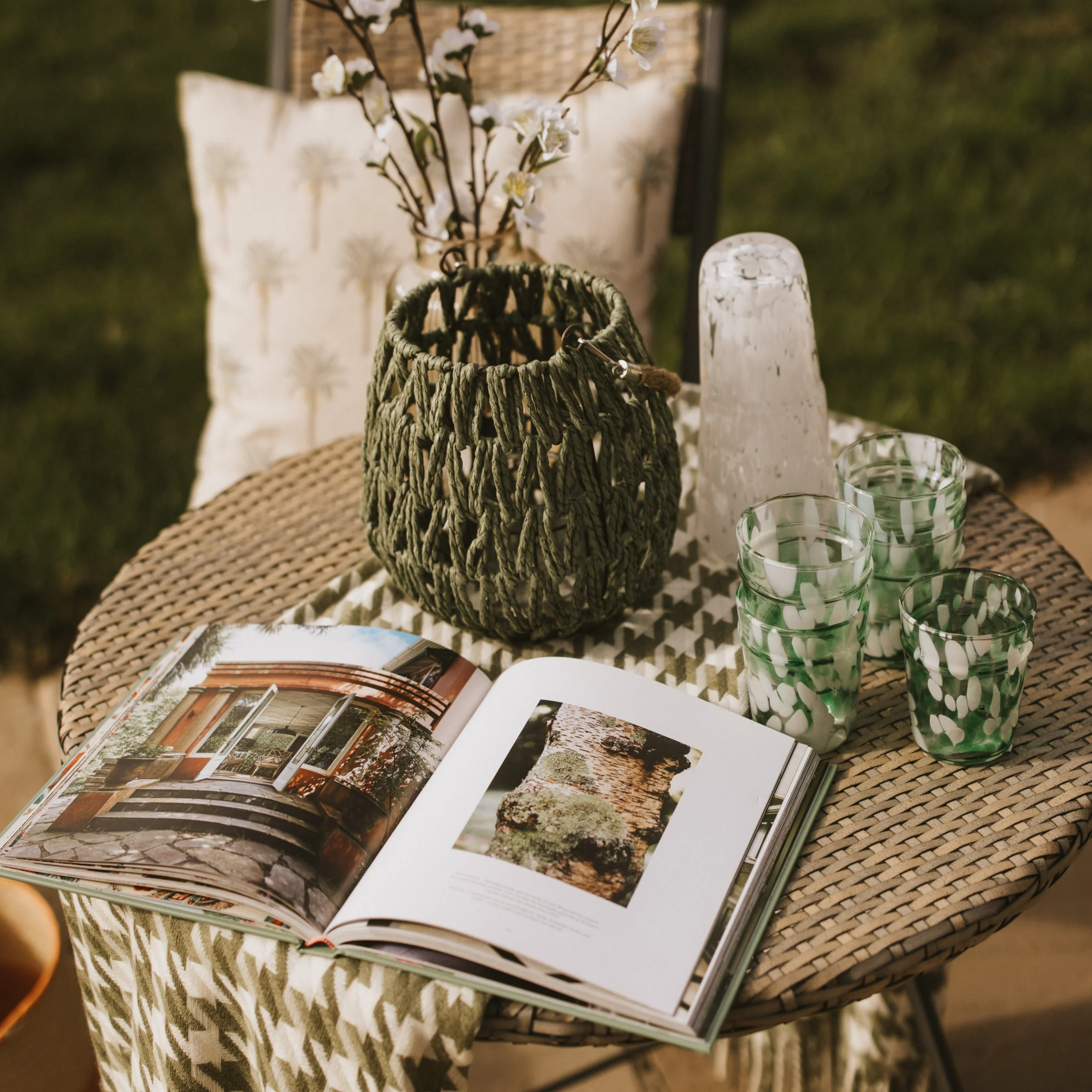A stylish flat lay of homeware with an open book, carafe and glasses