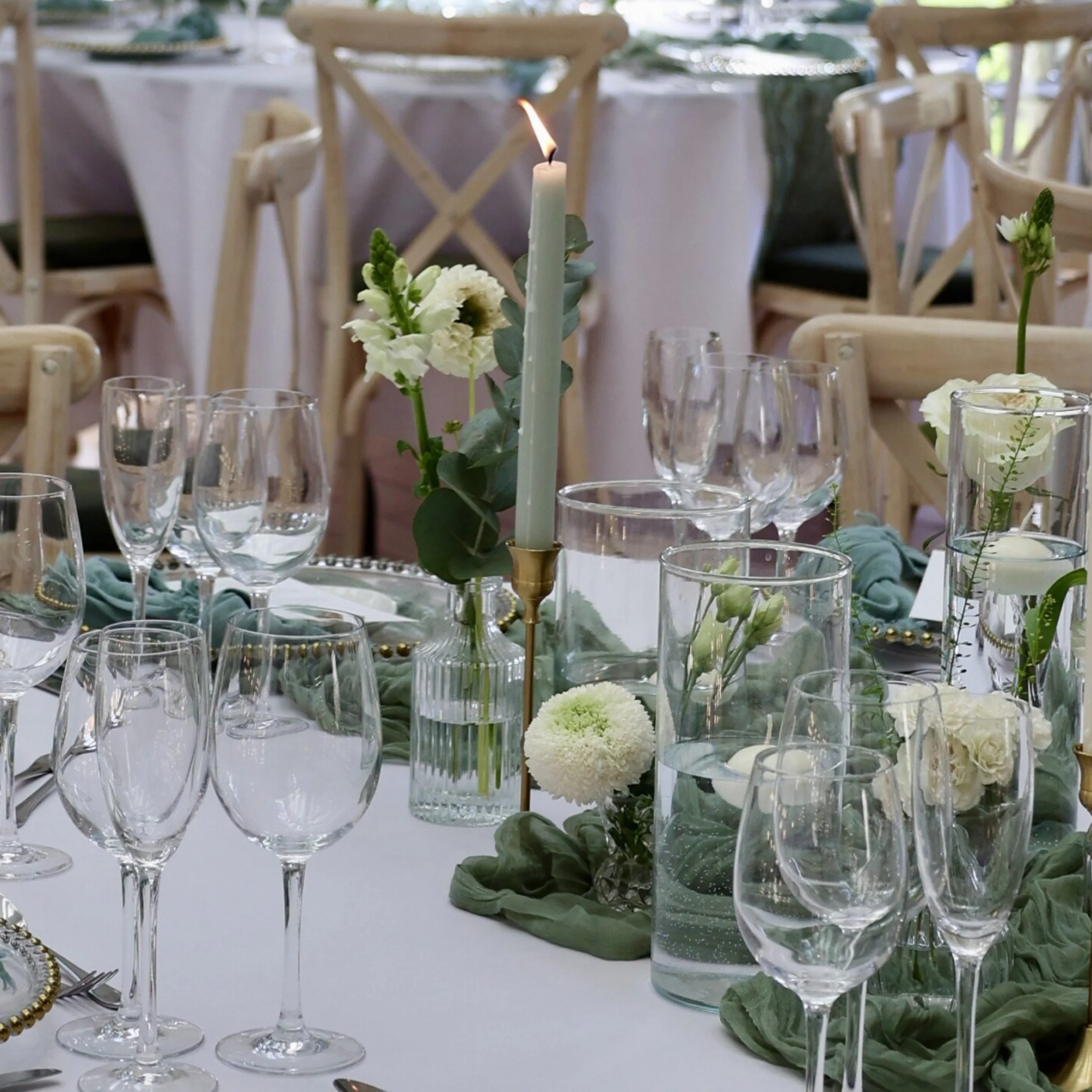 wedding table setting with glassware and green linen with pillar candles