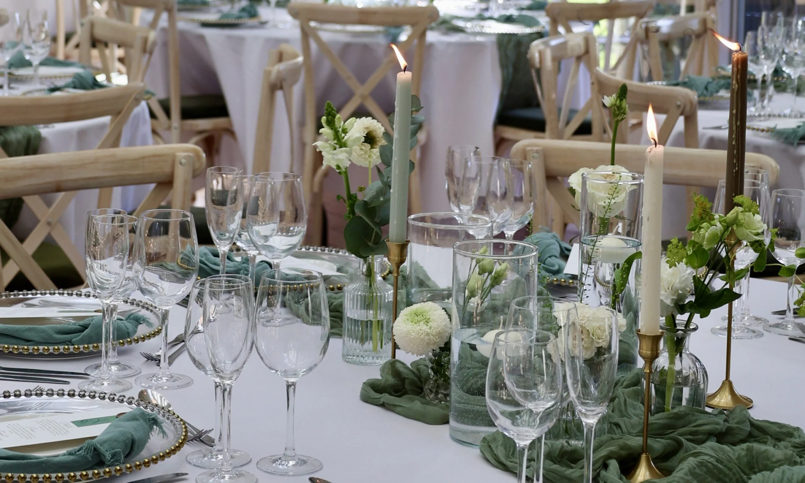 wedding table setting with glassware and green linen with pillar candles