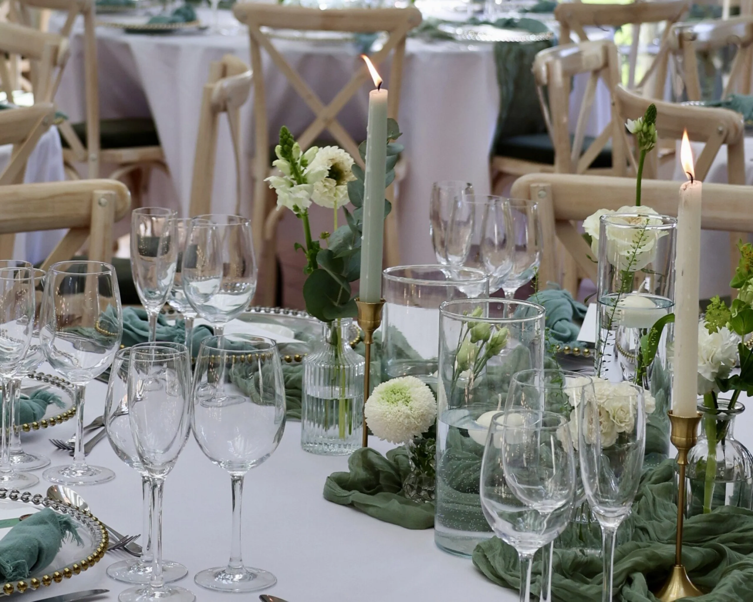 wedding table setting with glassware and green linen with pillar candles