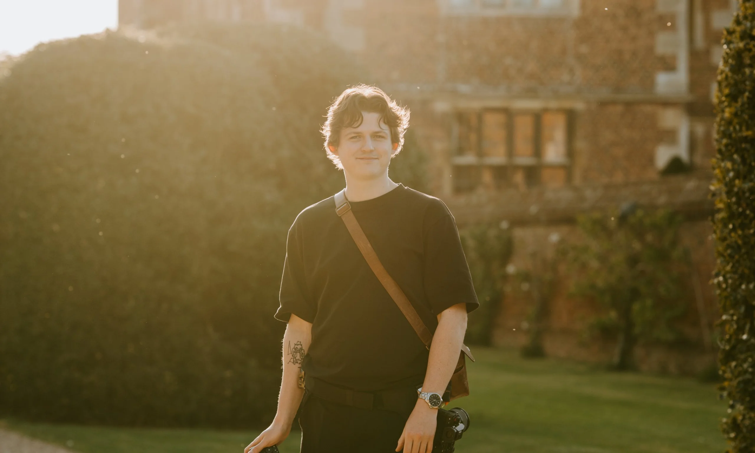 portrait photo of george hughes wedding photographer wearing black carrying cameras