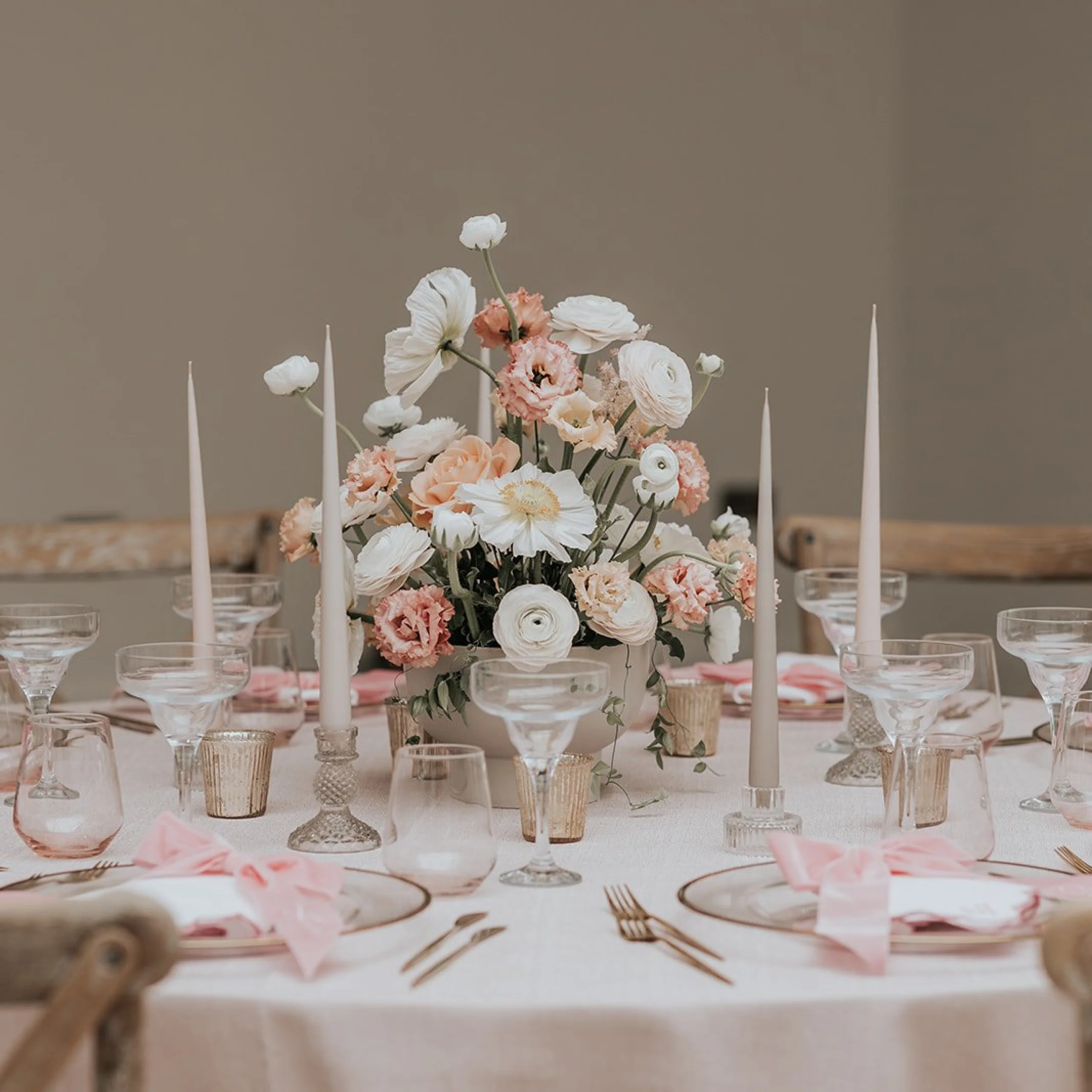 a pink and white wedding table scape with white pillar candles and bows