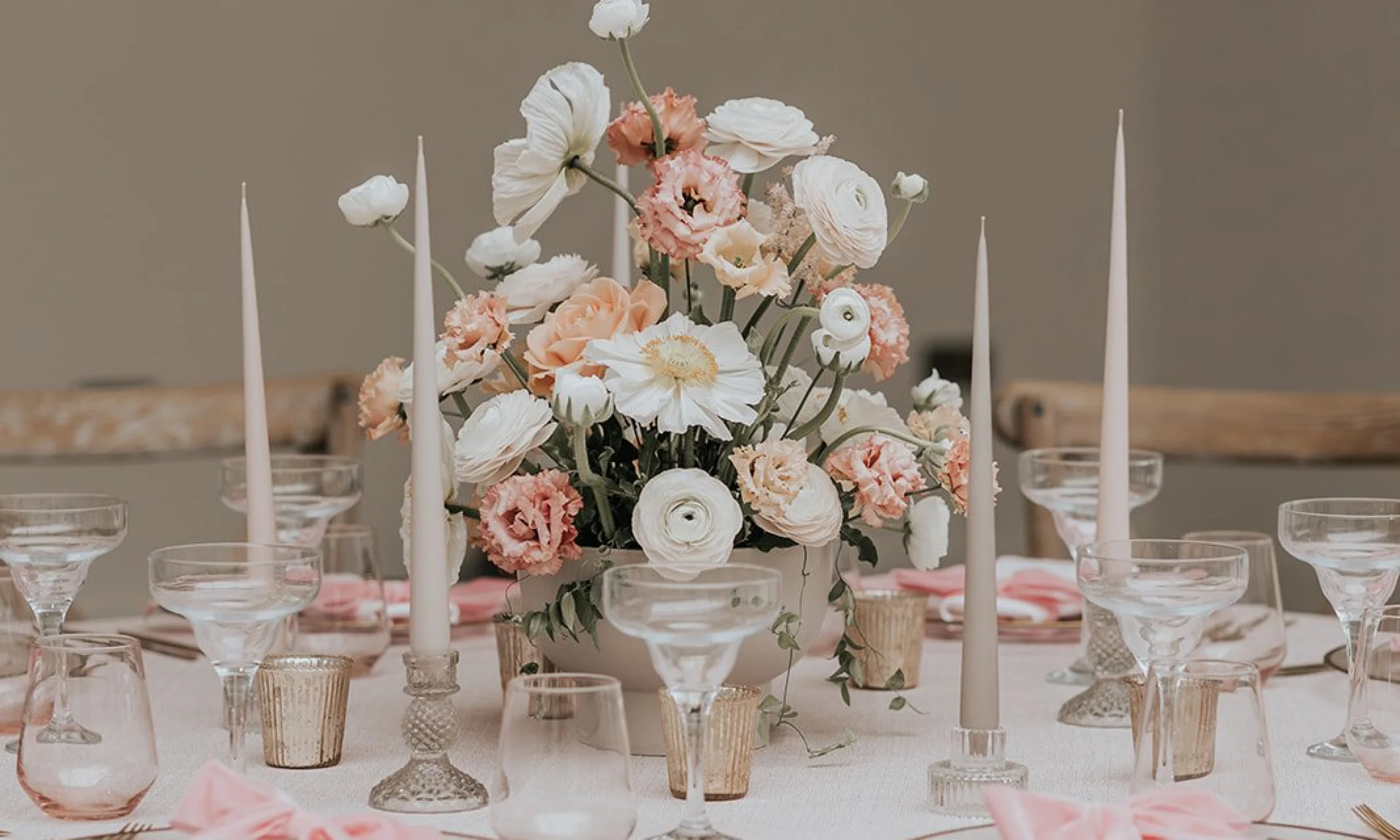 a pink and white wedding table scape with white pillar candles and bows