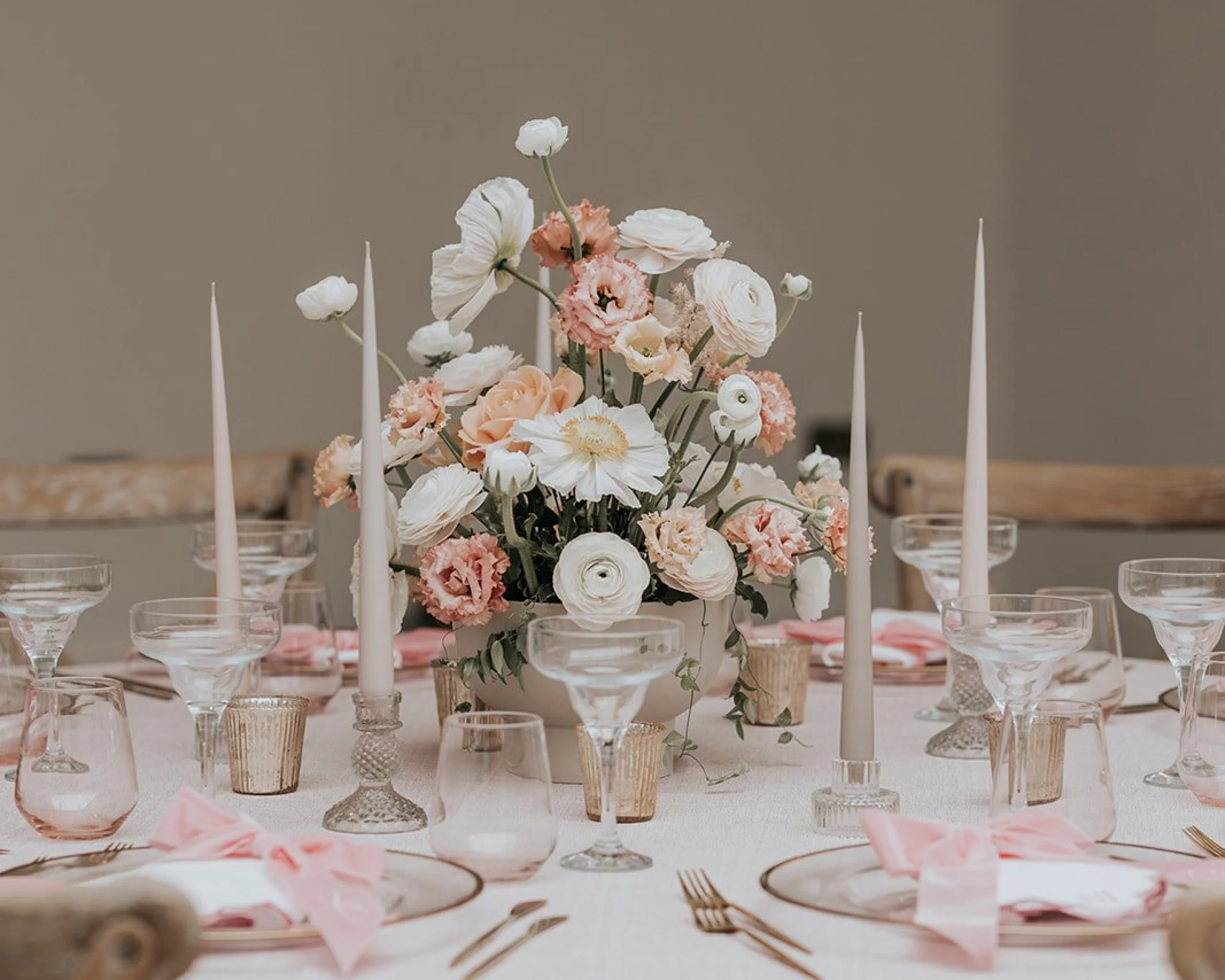 a pink and white wedding table scape with white pillar candles and bows