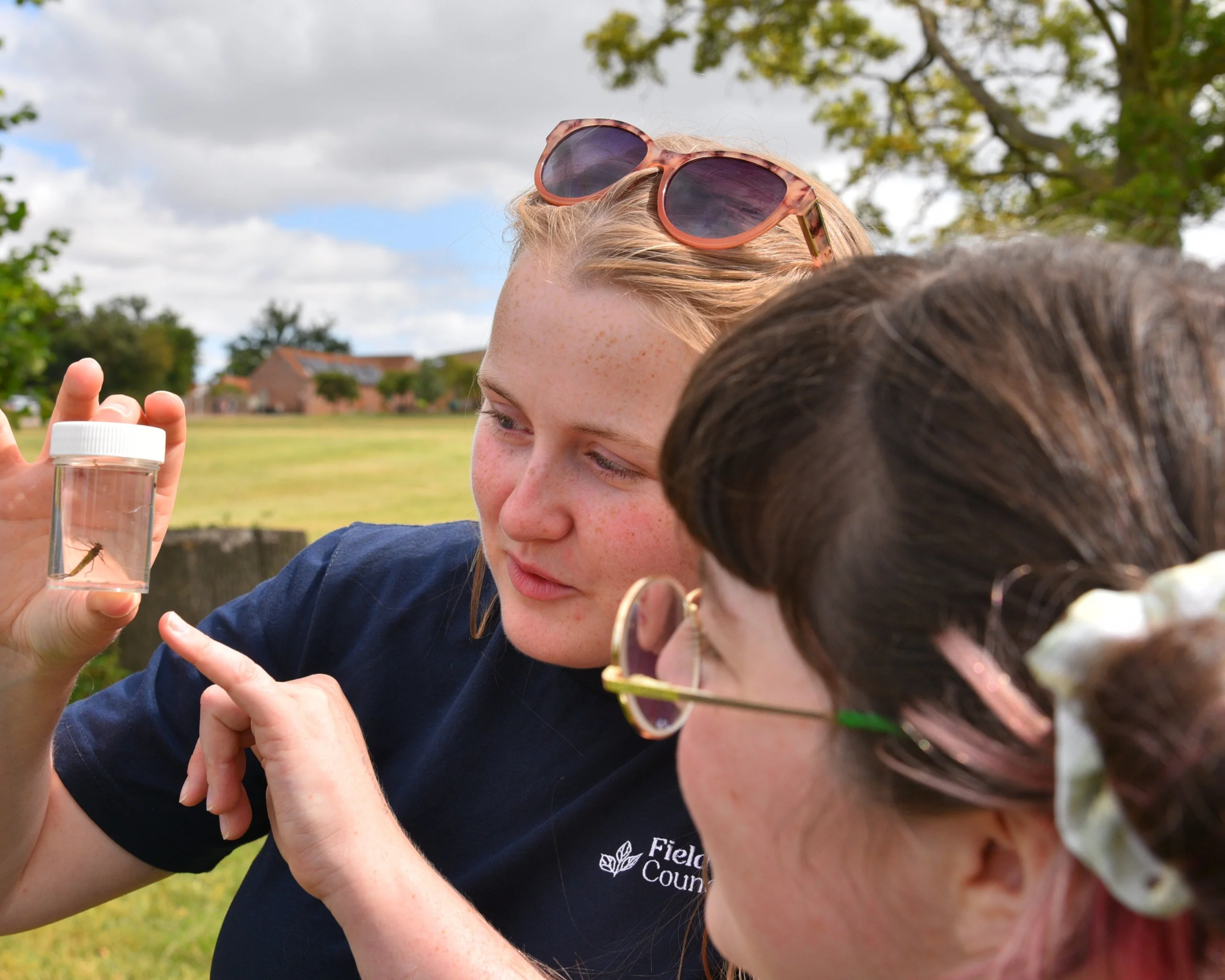 A tutor inspects an insect with a student