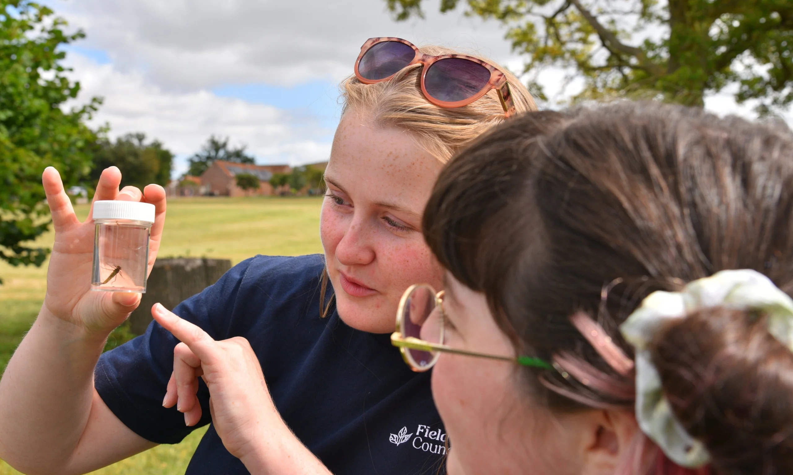 A tutor inspects an insect with a student