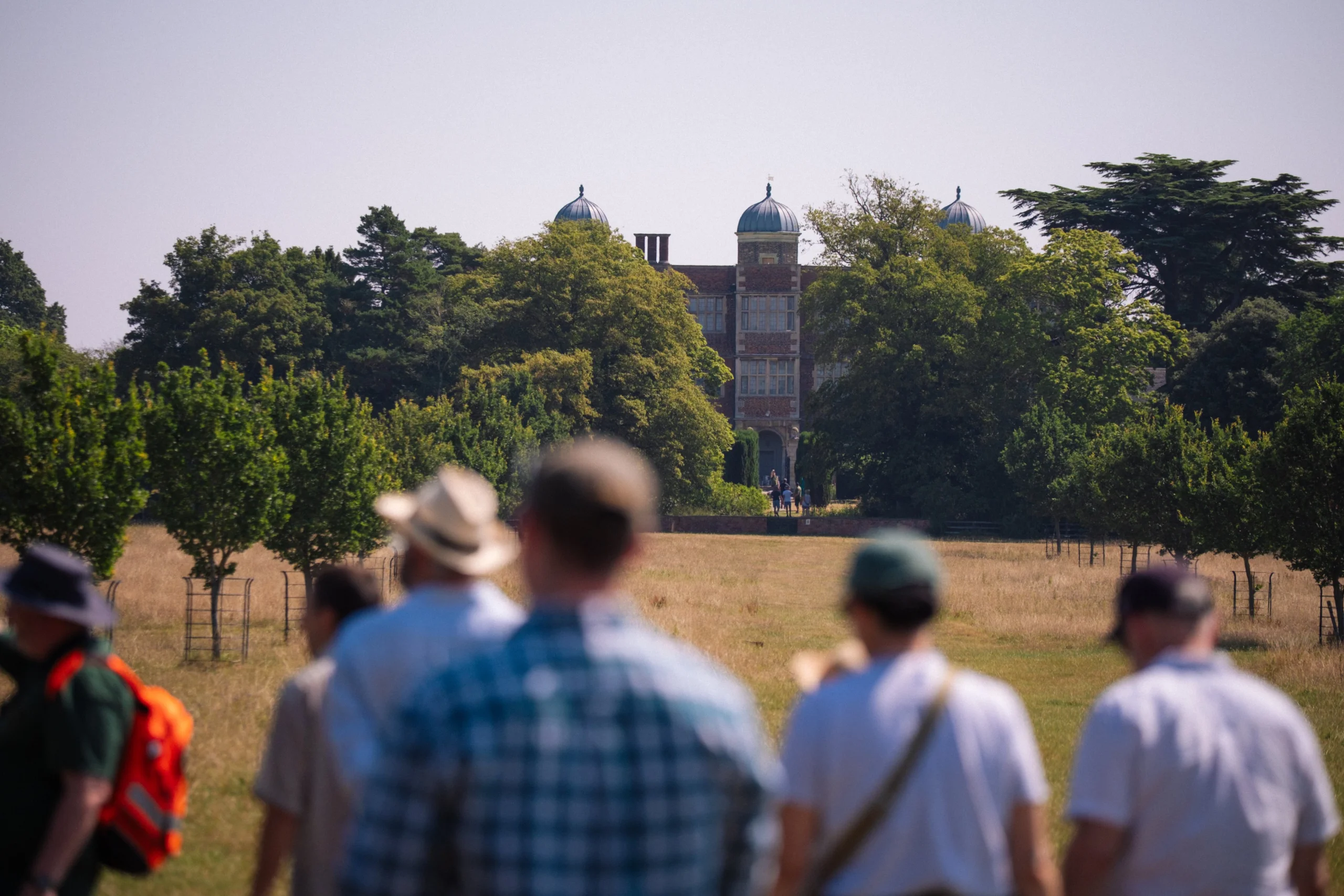 people walking through grass meadows on the doddington estate looking back at the elizabethan hall