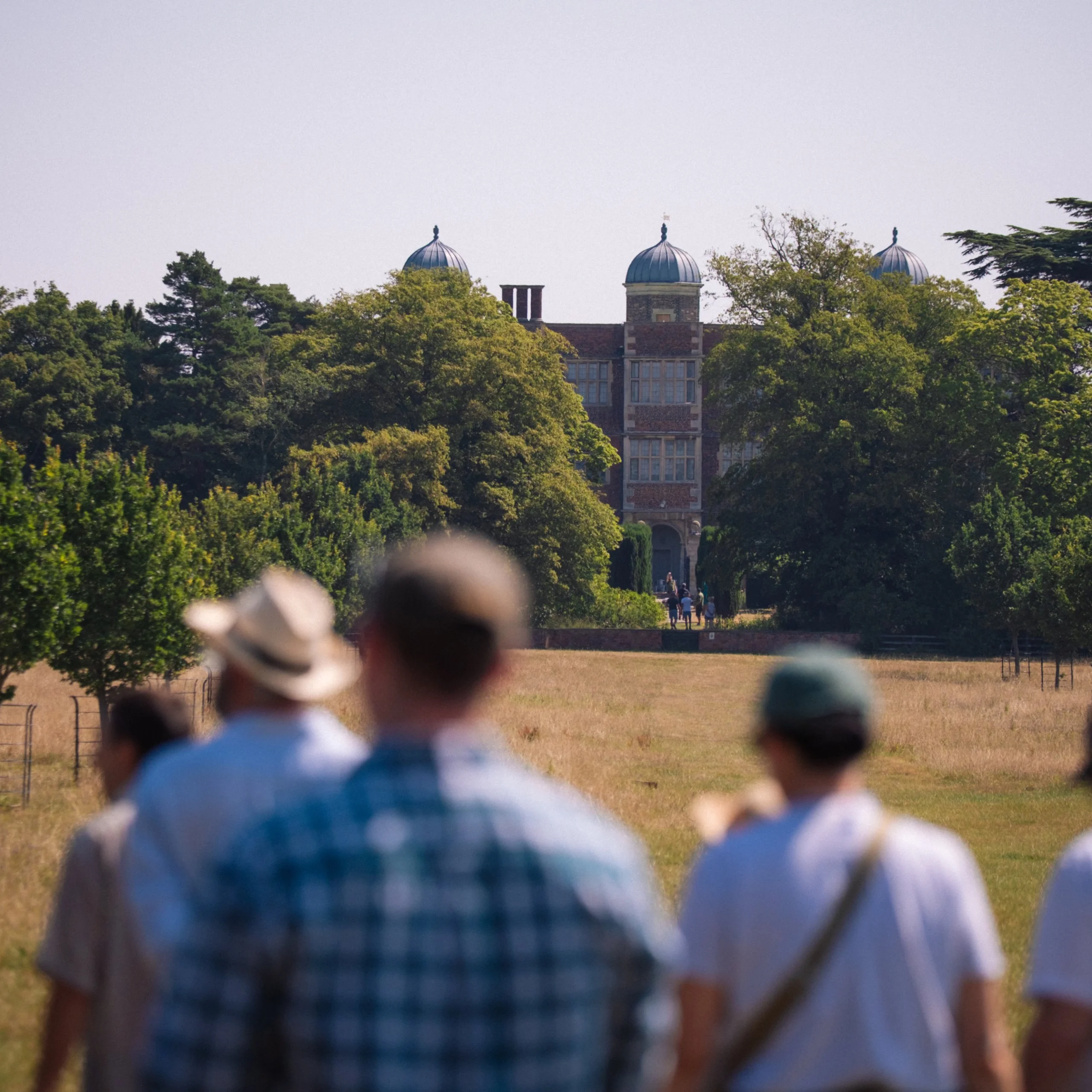 people walking through grass meadows on the doddington estate looking back at the elizabethan hall