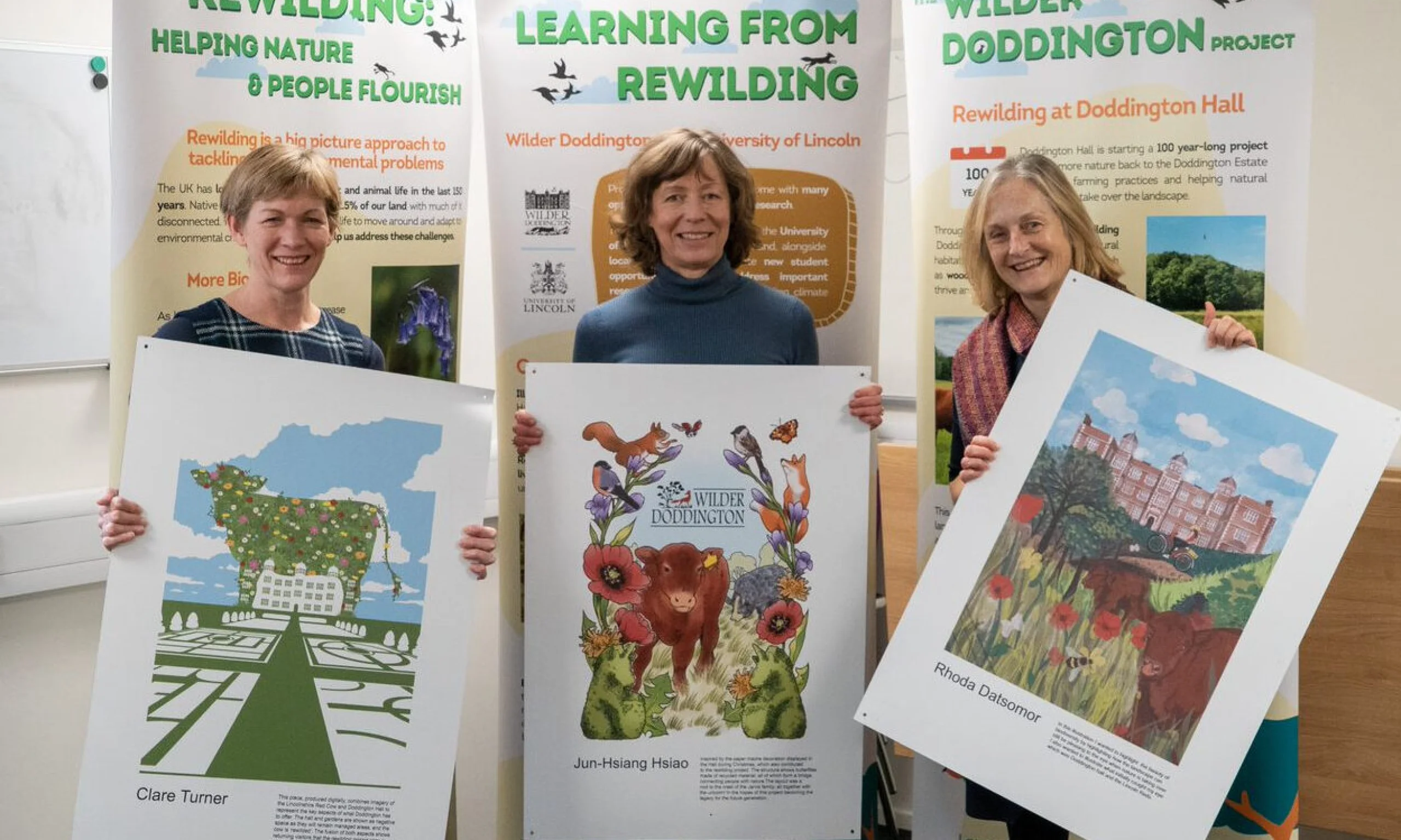 three women holding poster designs for wilder doddington