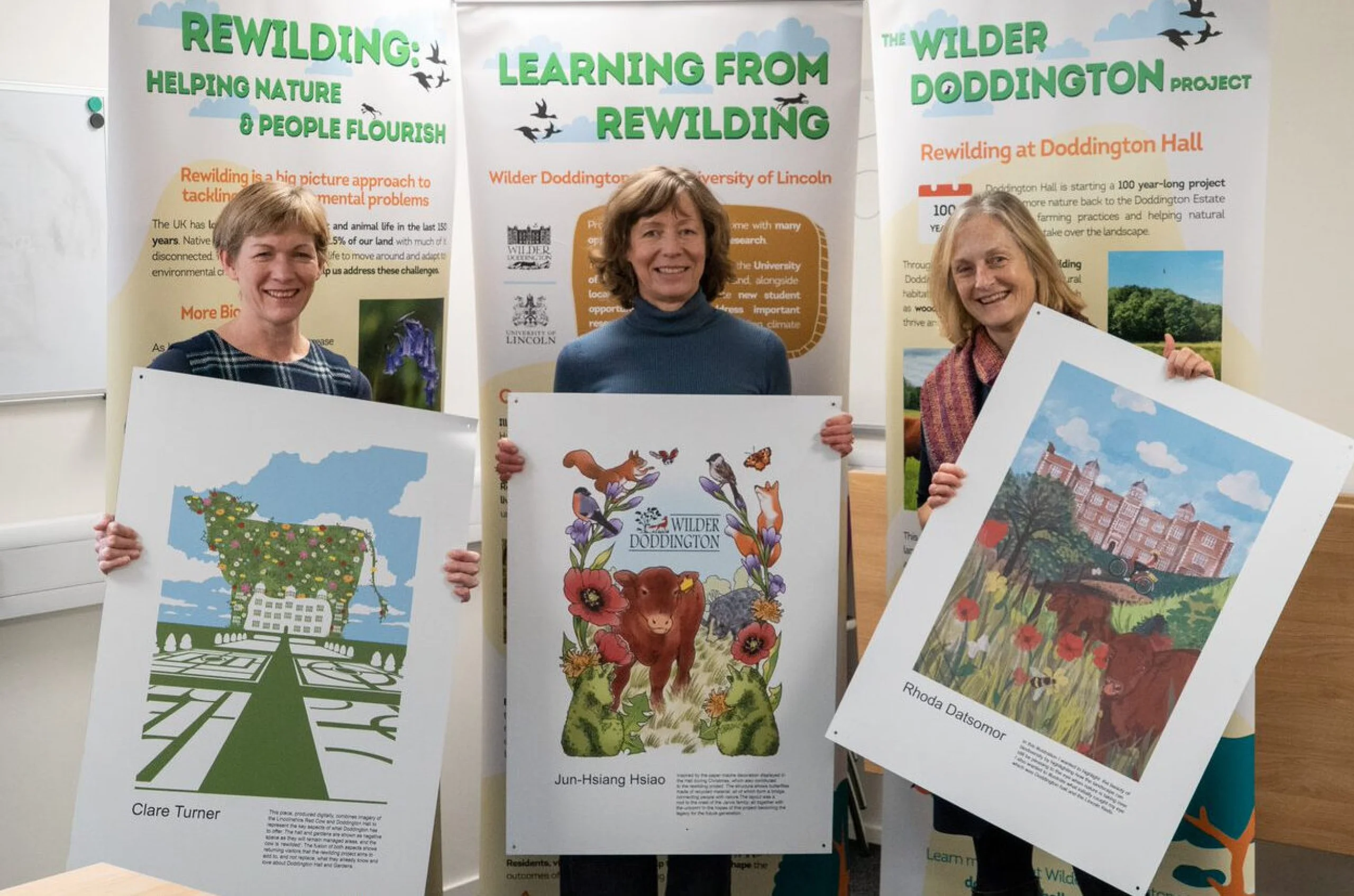 three women holding poster designs for wilder doddington