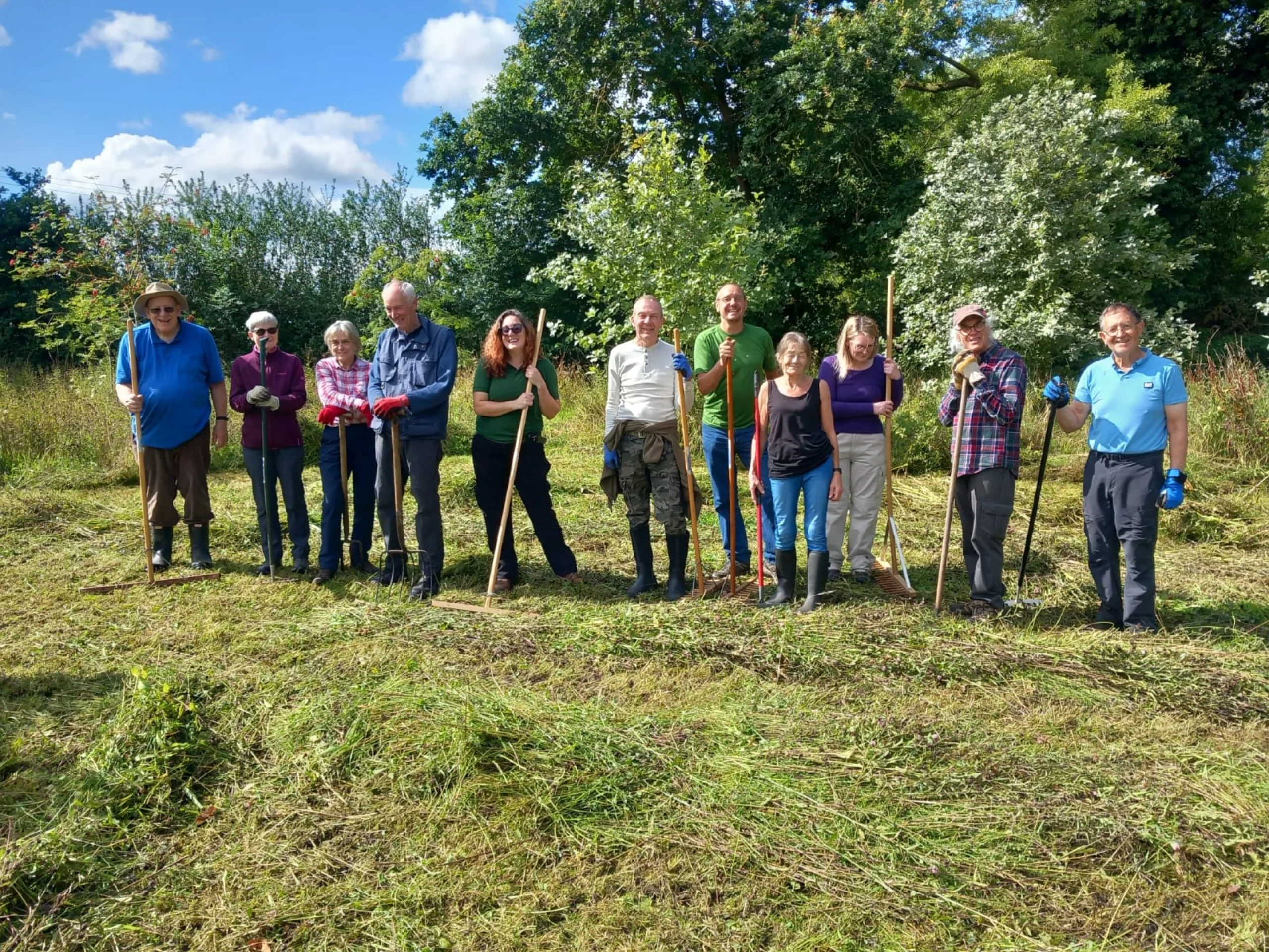 wilder doddington volunteers holding grass rakes in a field