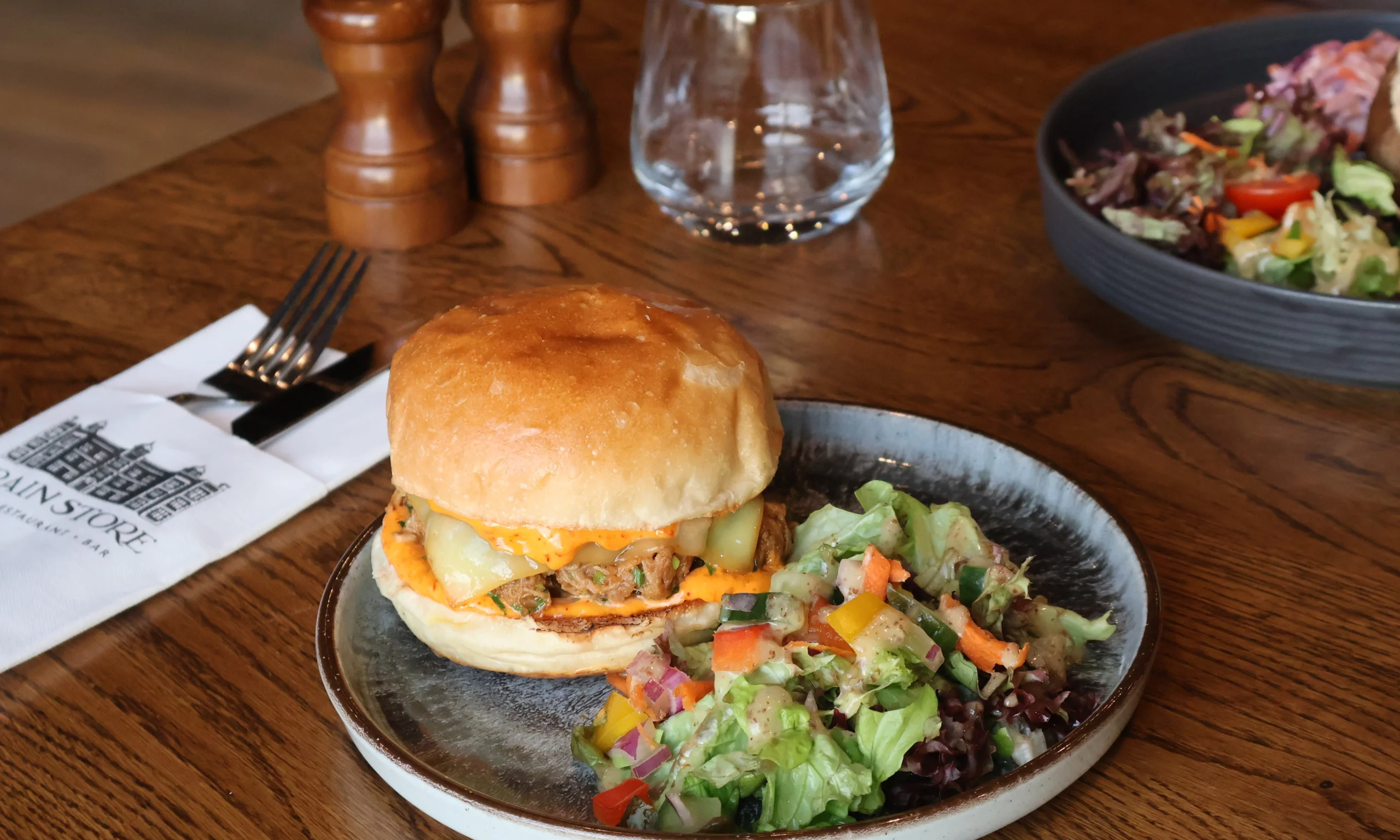 a pulled pork sandwich on a plate with salad at doddington hall grain store