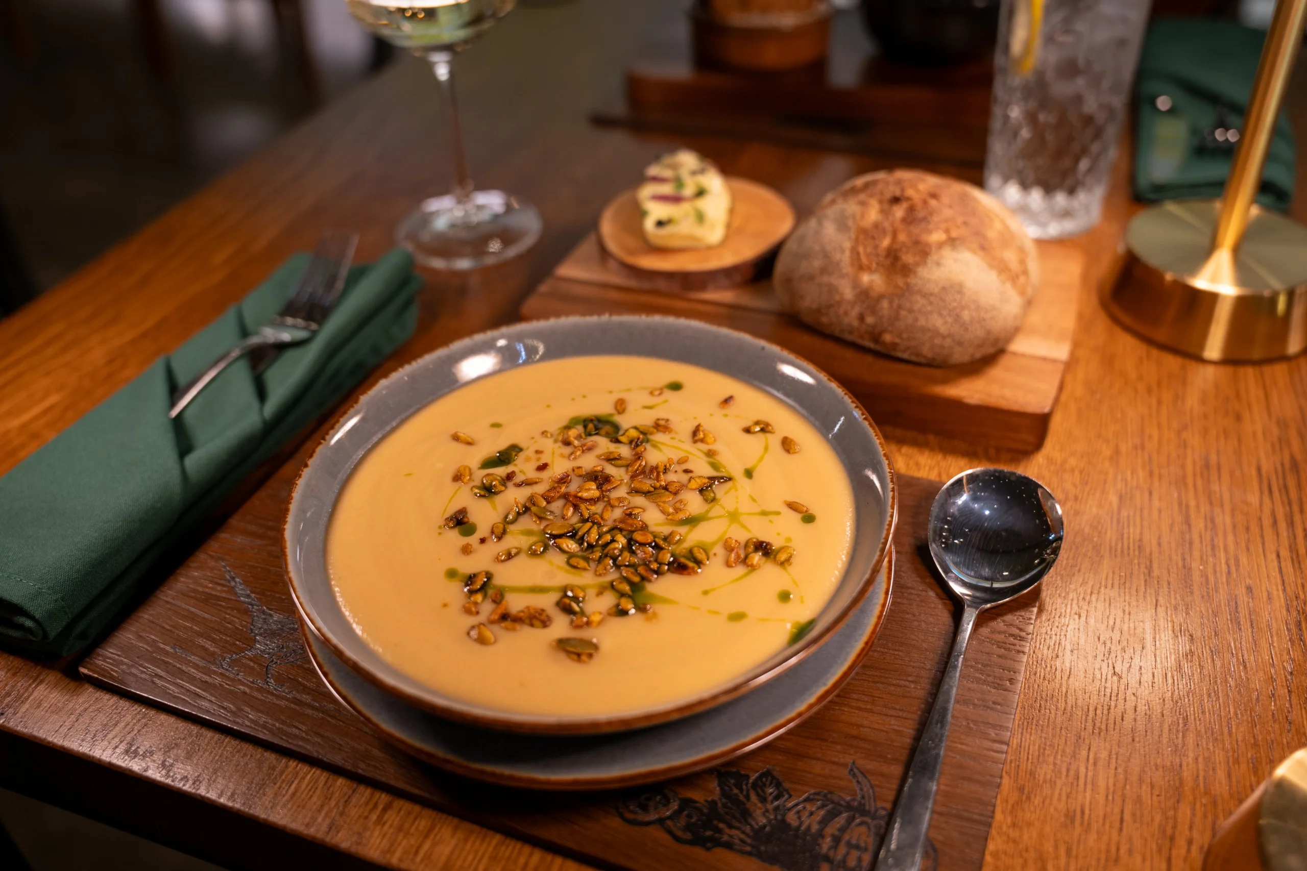 a bowl of pumpkin soup garnished with seeds and basil oil at doddington hall grain store