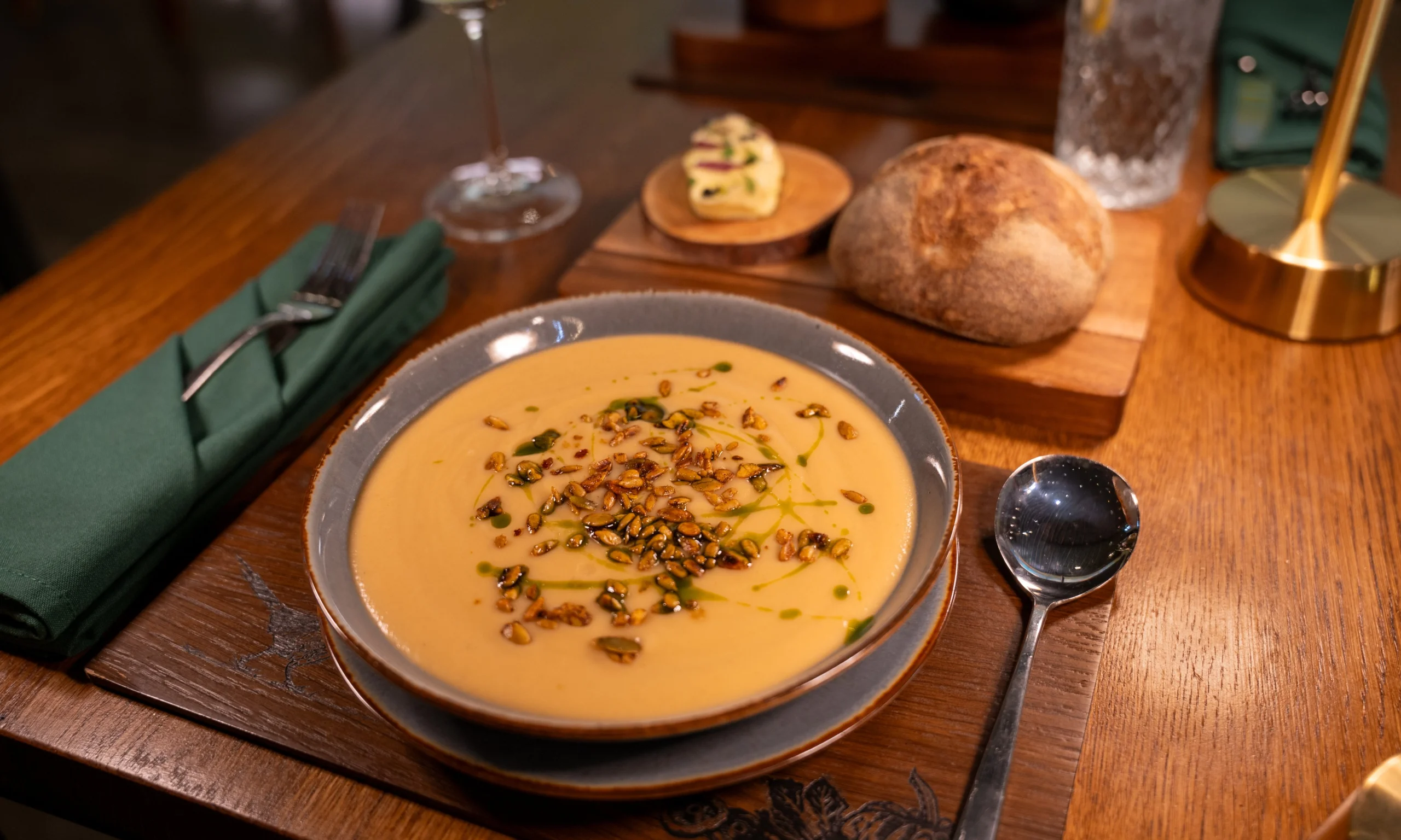 a bowl of pumpkin soup garnished with seeds and basil oil at doddington hall grain store