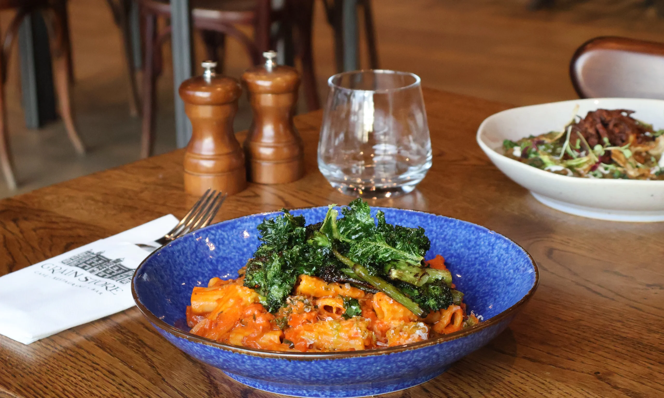 a blue ceramic bowl with rigatoni pasta and broccoli at the grain store doddington hall
