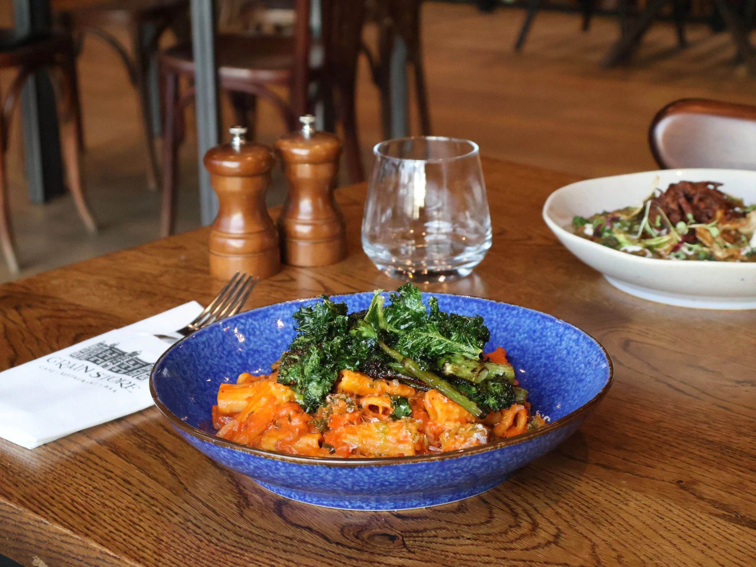 a blue ceramic bowl with rigatoni pasta and broccoli at the grain store doddington hall