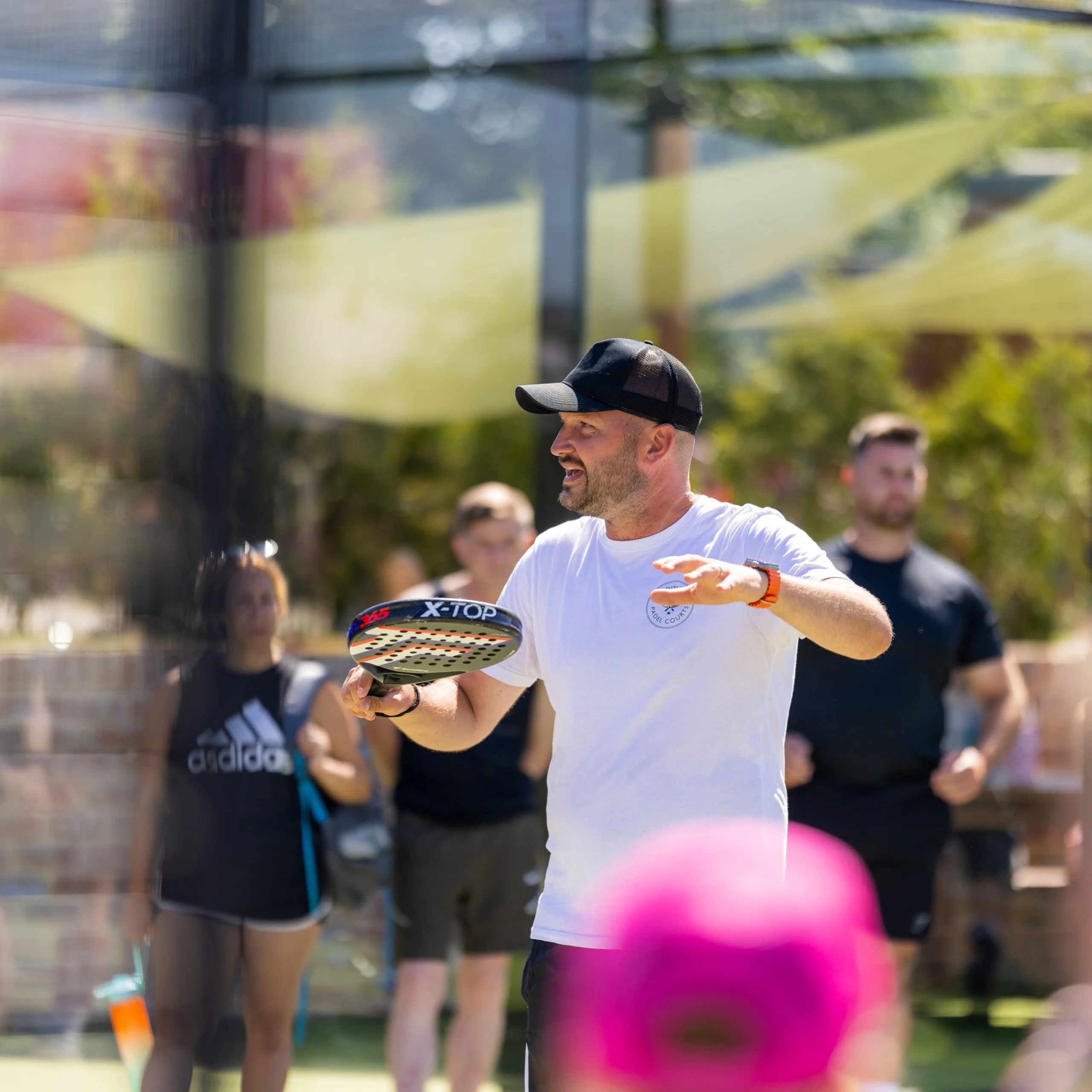 a male padel coach talking to people at doddington hall padel courts