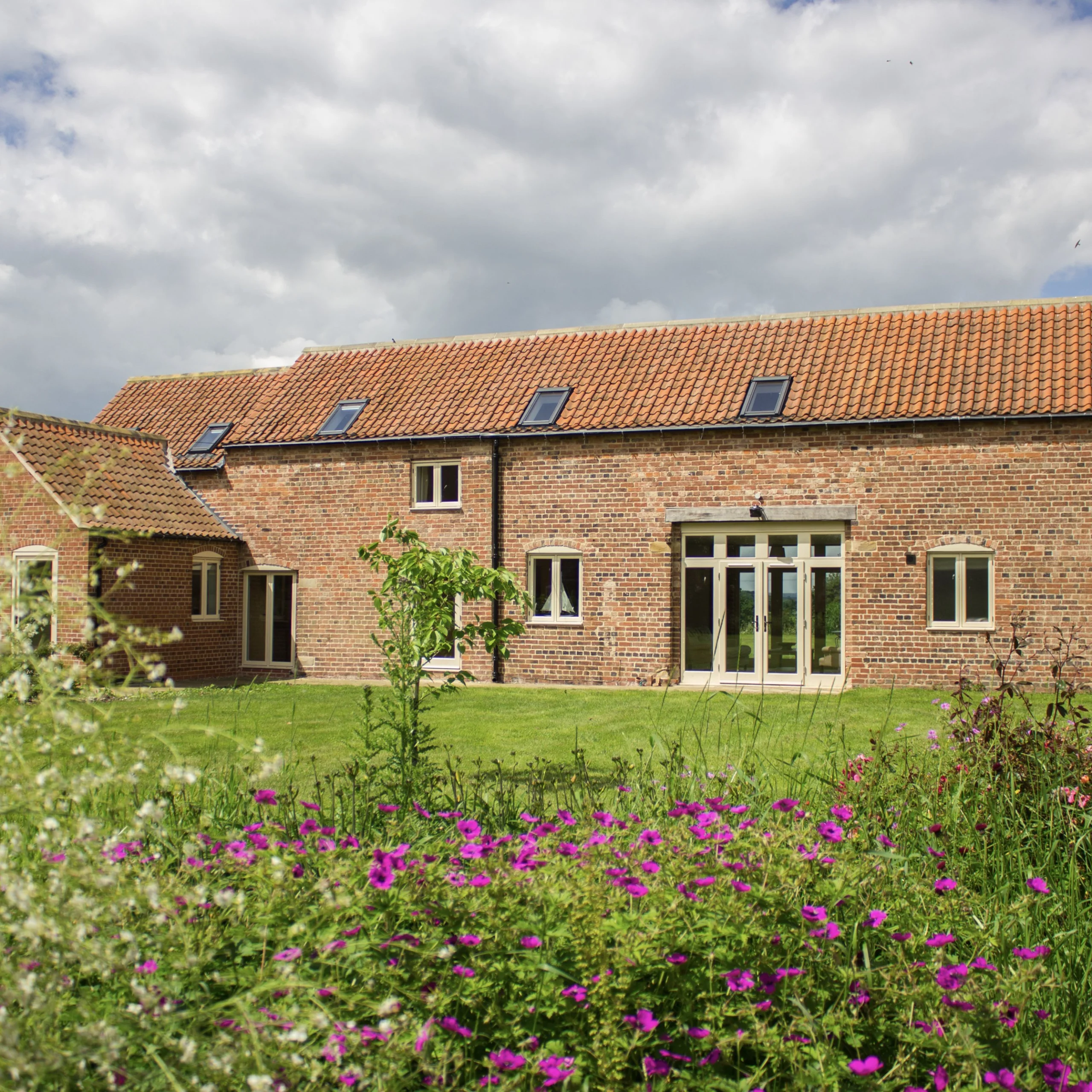 a brick clad cottage exterior with garden and flowers at doddington hall