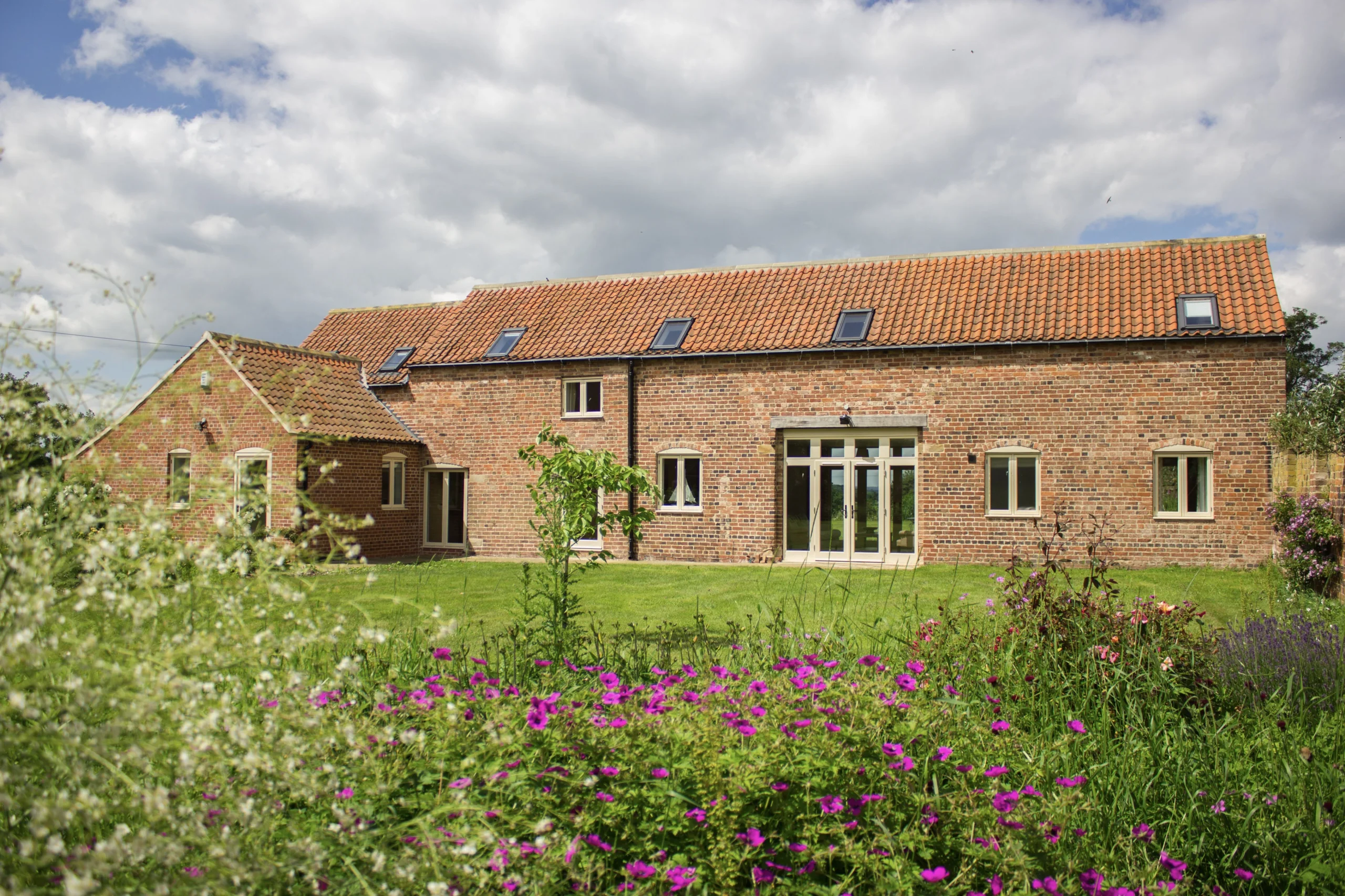 a brick clad cottage exterior with garden and flowers at doddington hall