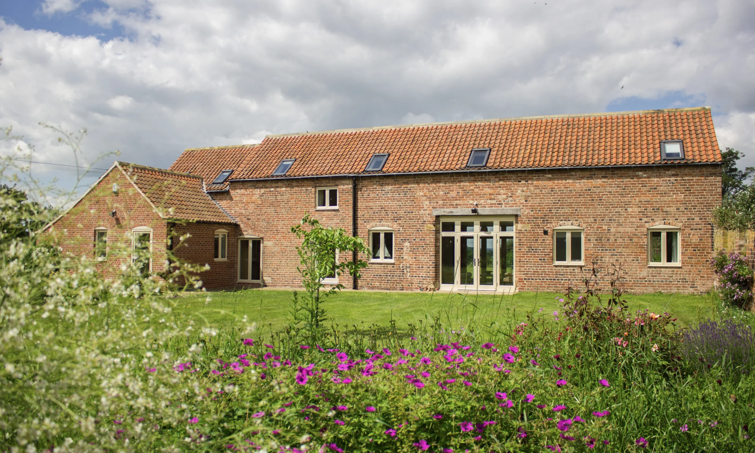 a brick clad cottage exterior with garden and flowers at doddington hall