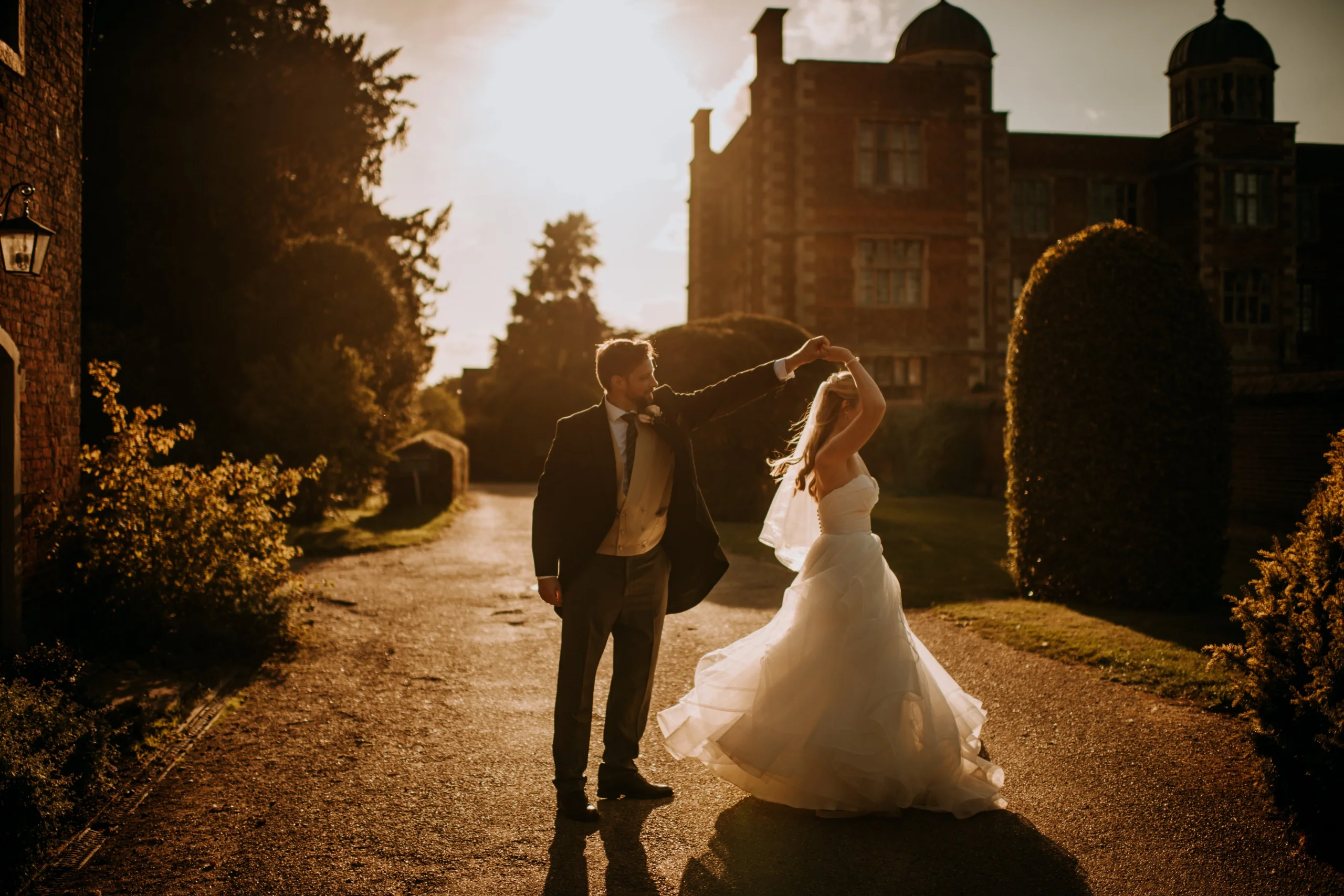 a bride and groom dancing in sunset lighting in the garden at doddington hall