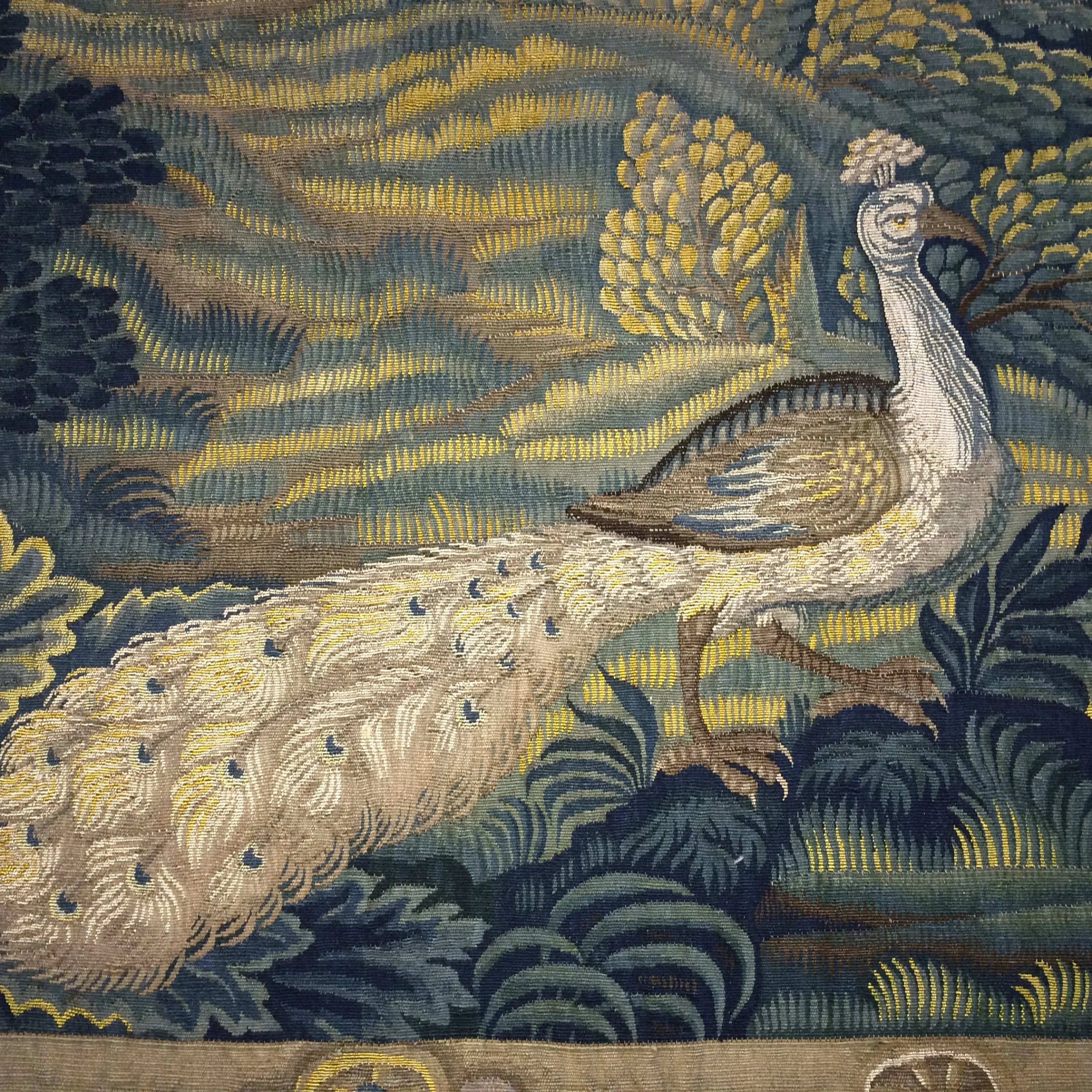 a close up of a peacock embroidered into a tapestry at doddington hall