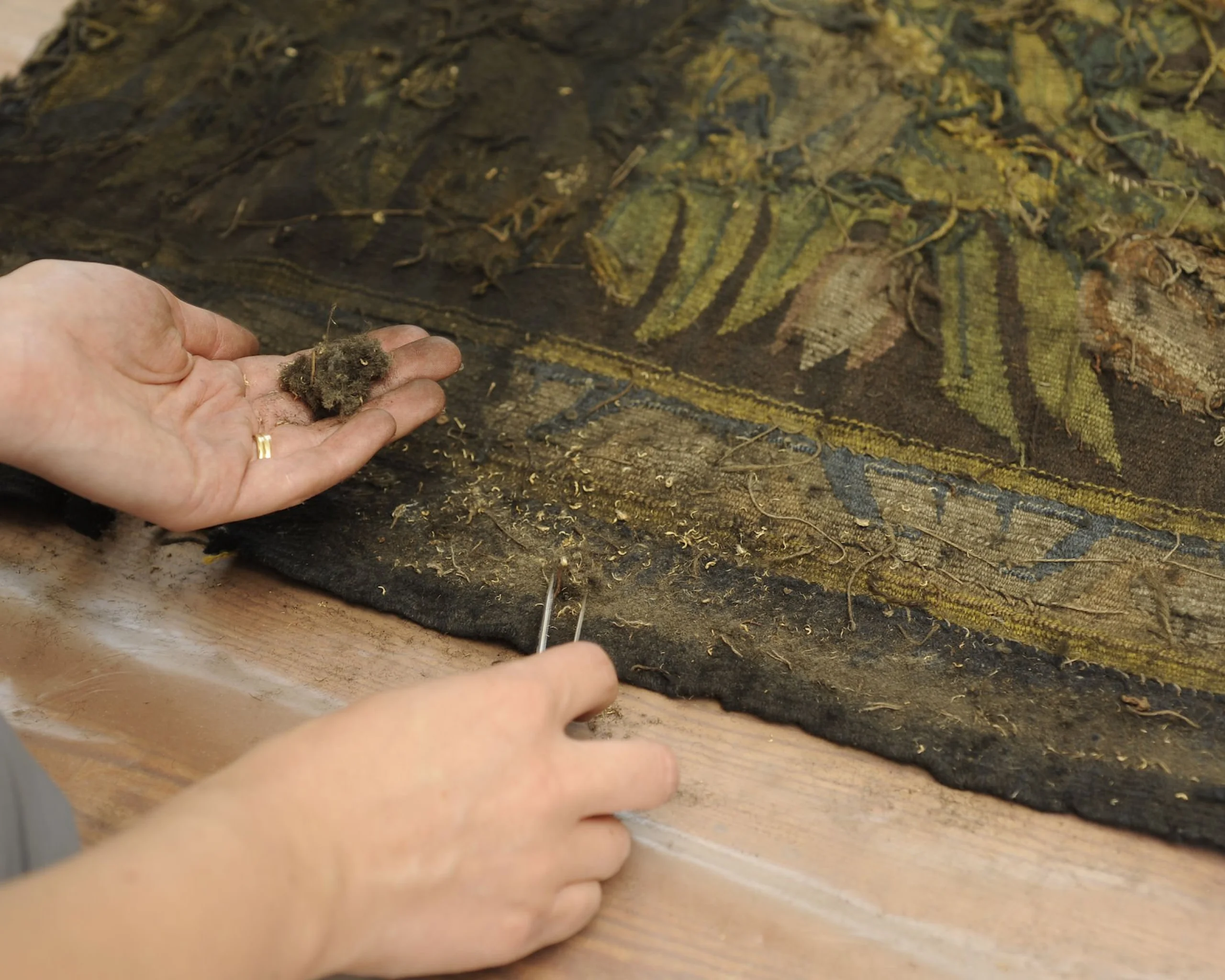 conservation artist working with tweezers on a tapestry