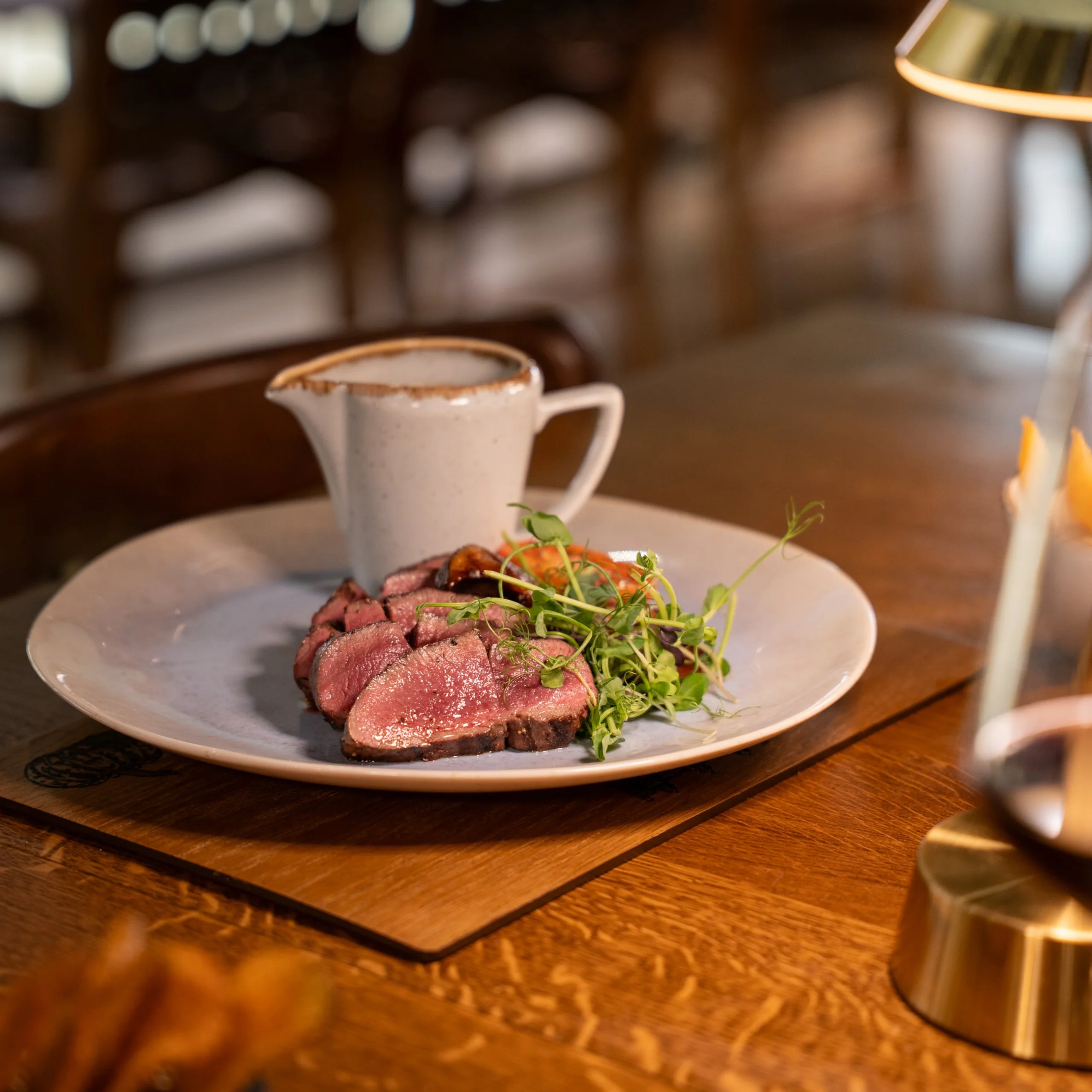 sliced venison with a gravy jug on a wooden table at doddington hall