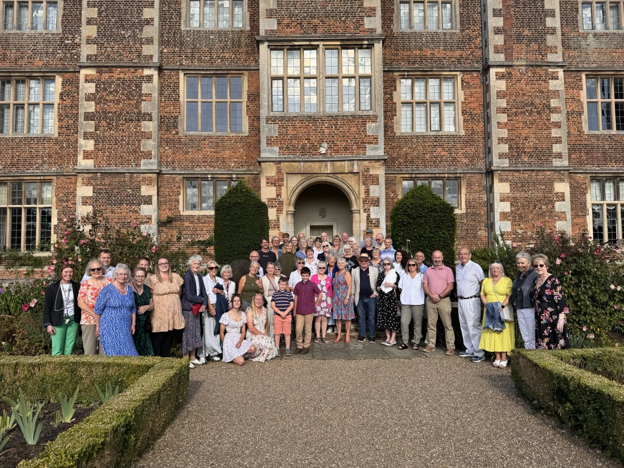 a group of people stood in front of doddington hall in summer