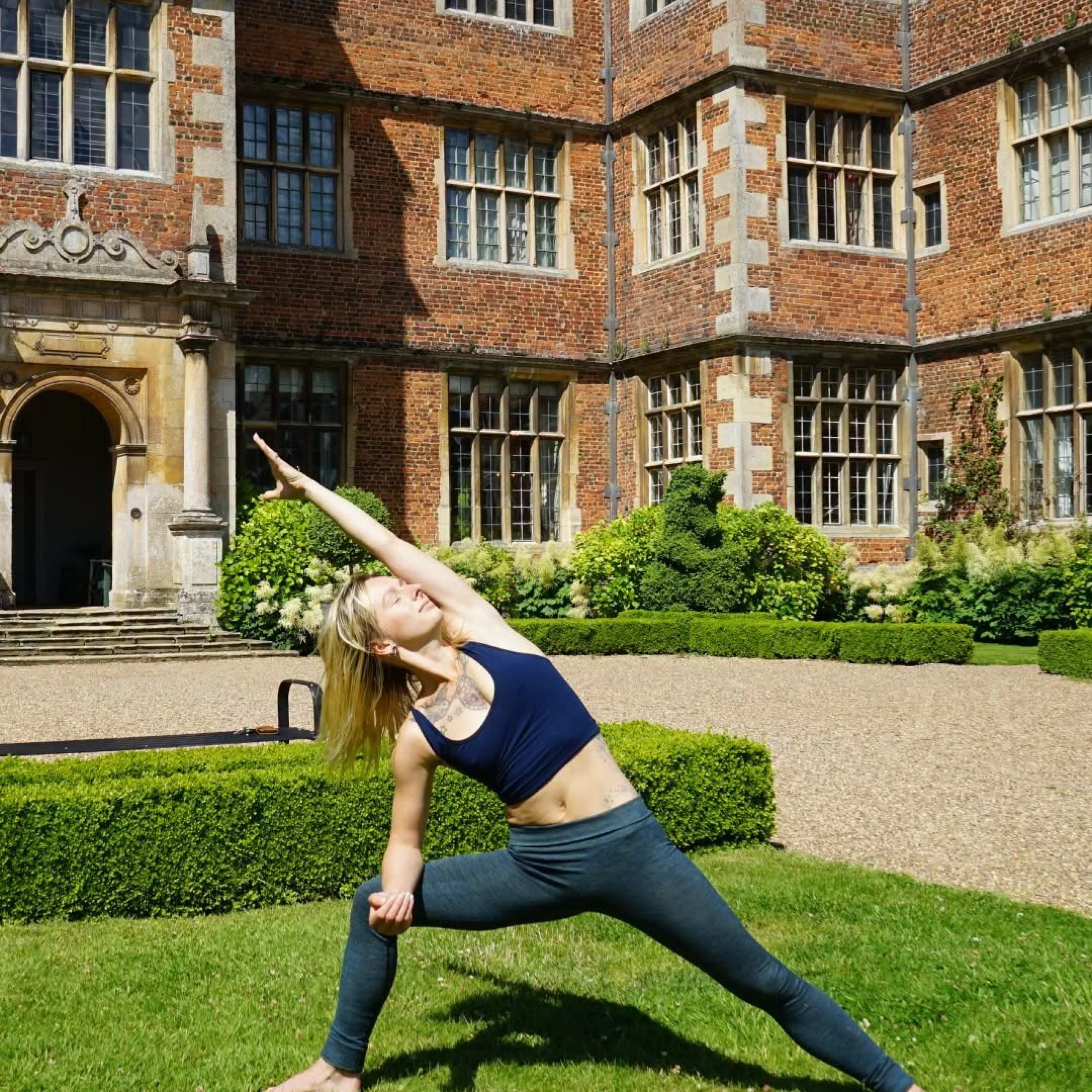 lady in yoga outfit performing a yoga stretch on the lawn in front of doddington hall